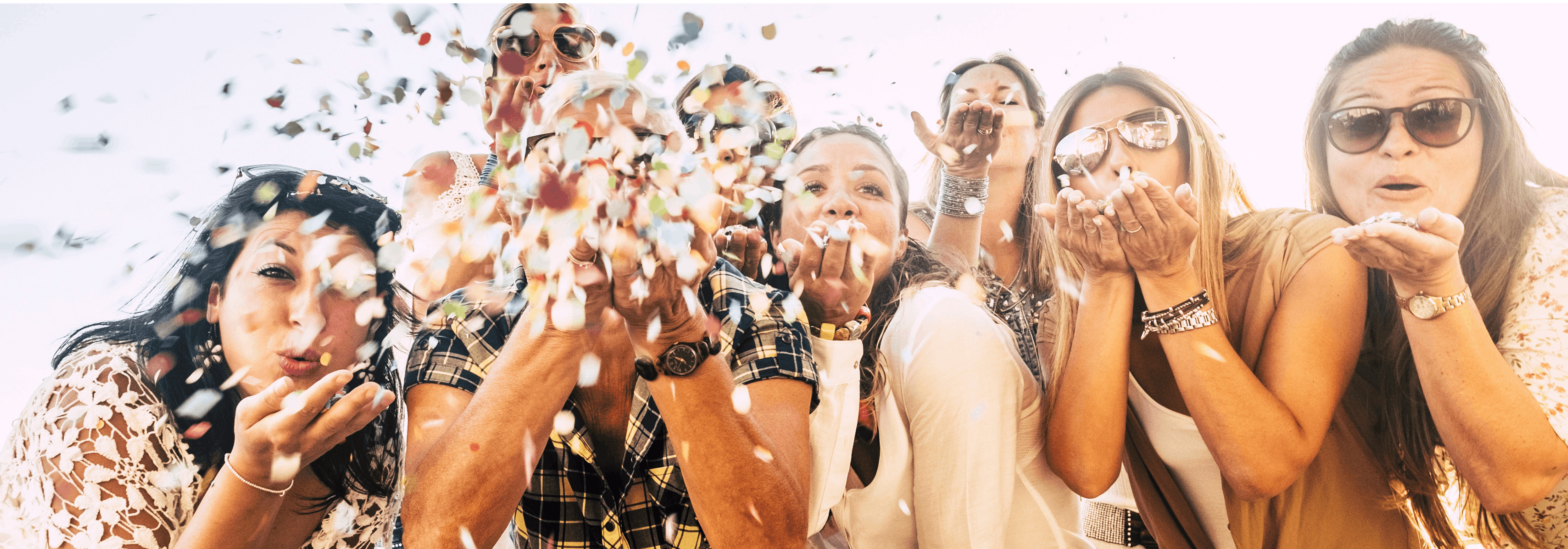 Group of friends blowing confetti as they celebrate a special occasion together