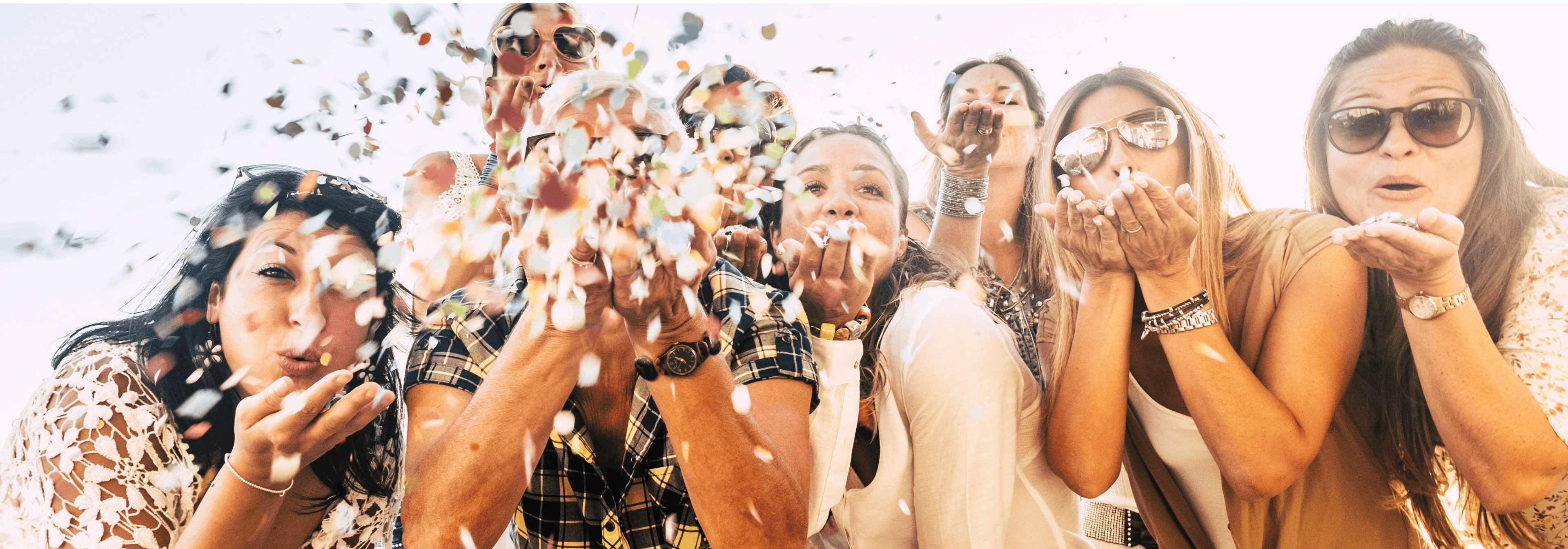 Group of friends blowing confetti as they celebrate a special occasion together