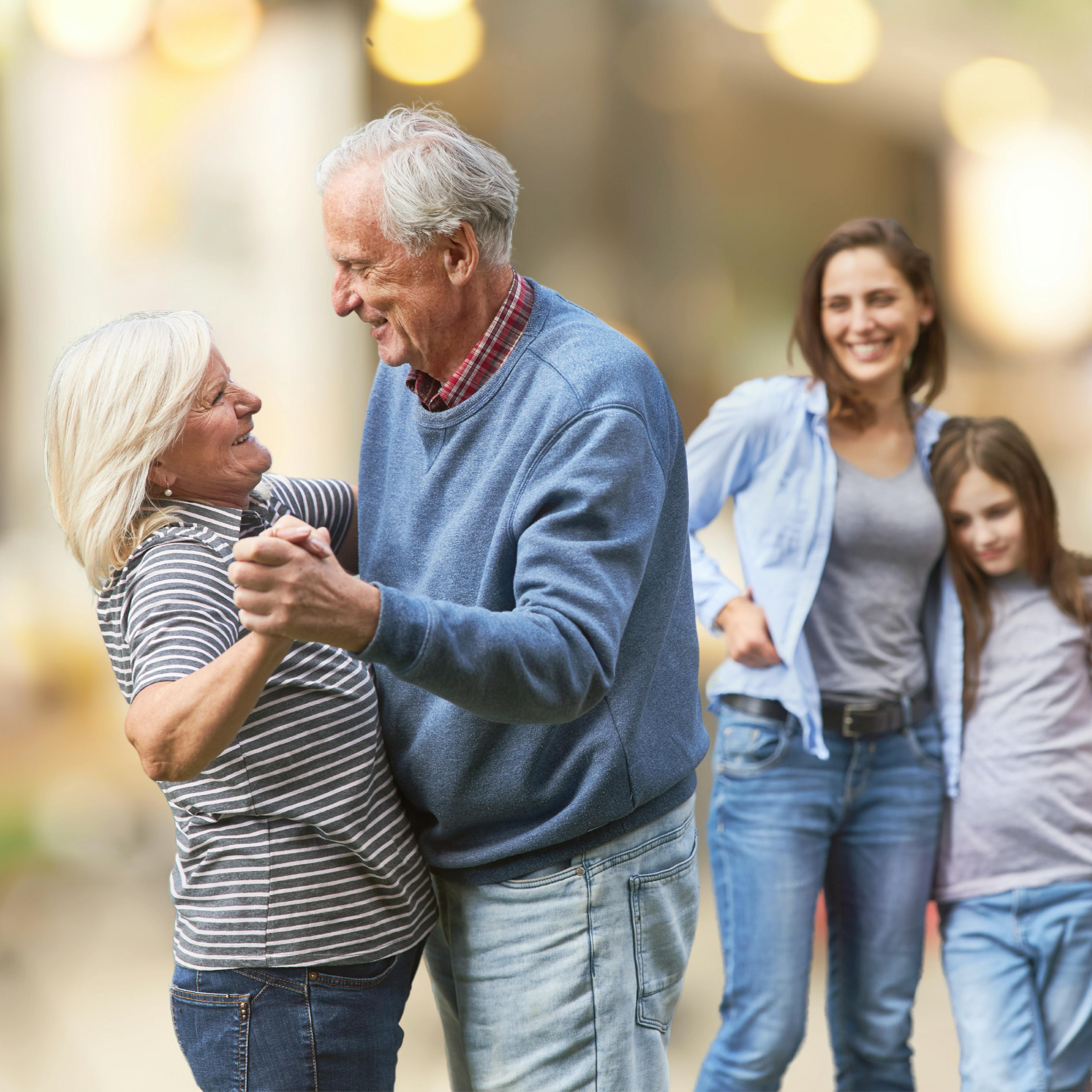 Retired couple smiling and dancing as their family smiles and looks on, by Woxbox Gift