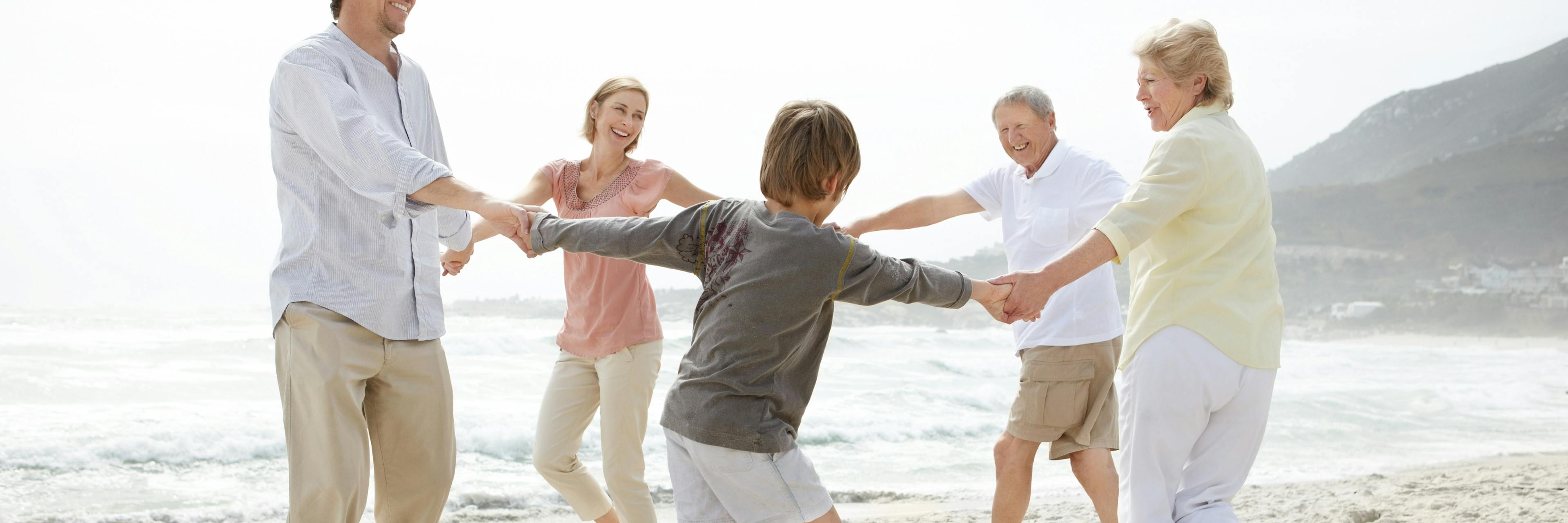 Multi generational family having fun and holding hands in a circle on the beach, by Woxbox Gift