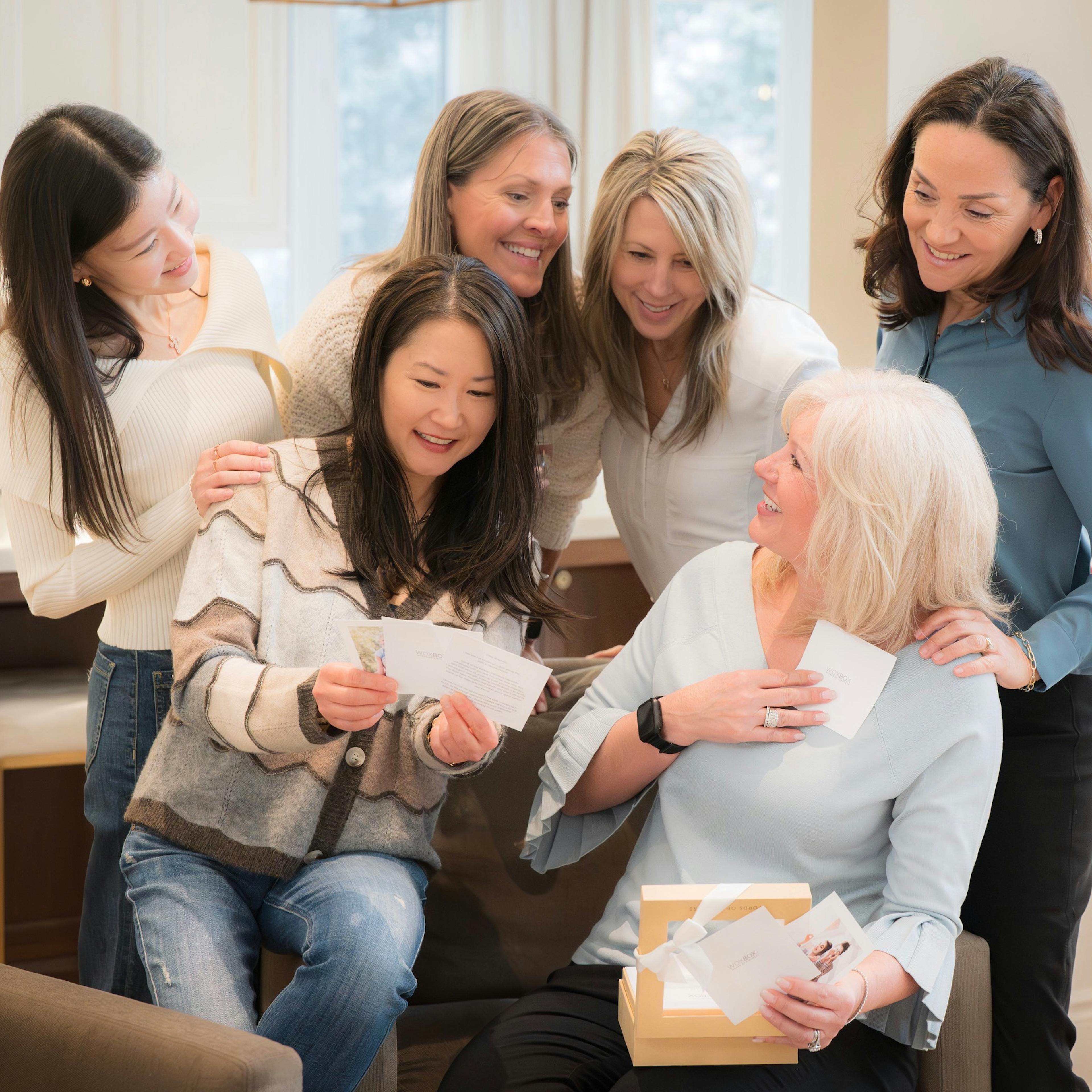 Woman smiling while opening her Woxbox Gift with friends gathered around her