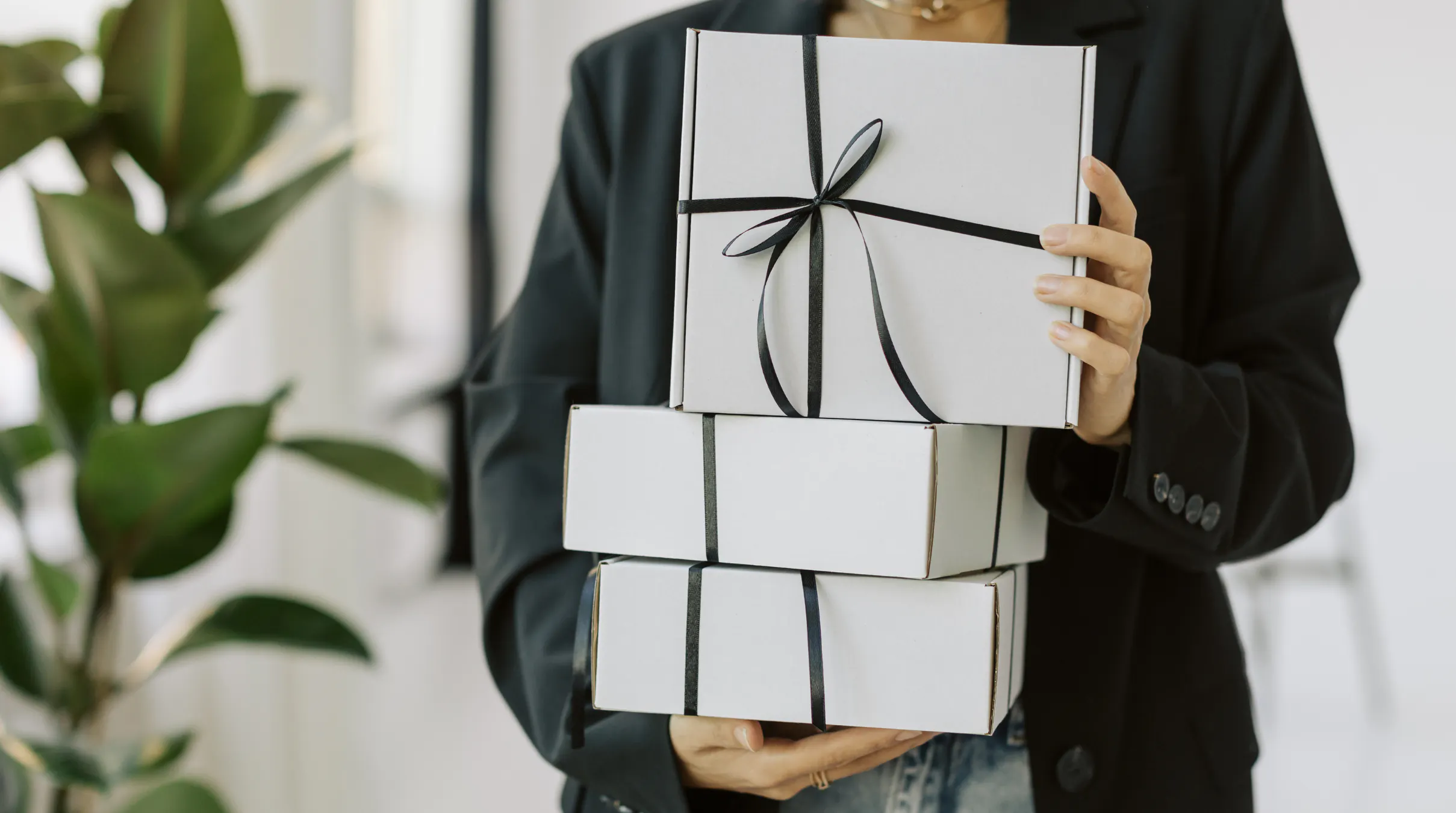 Woman holding co-worker gift boxes wrapped in black ribbon