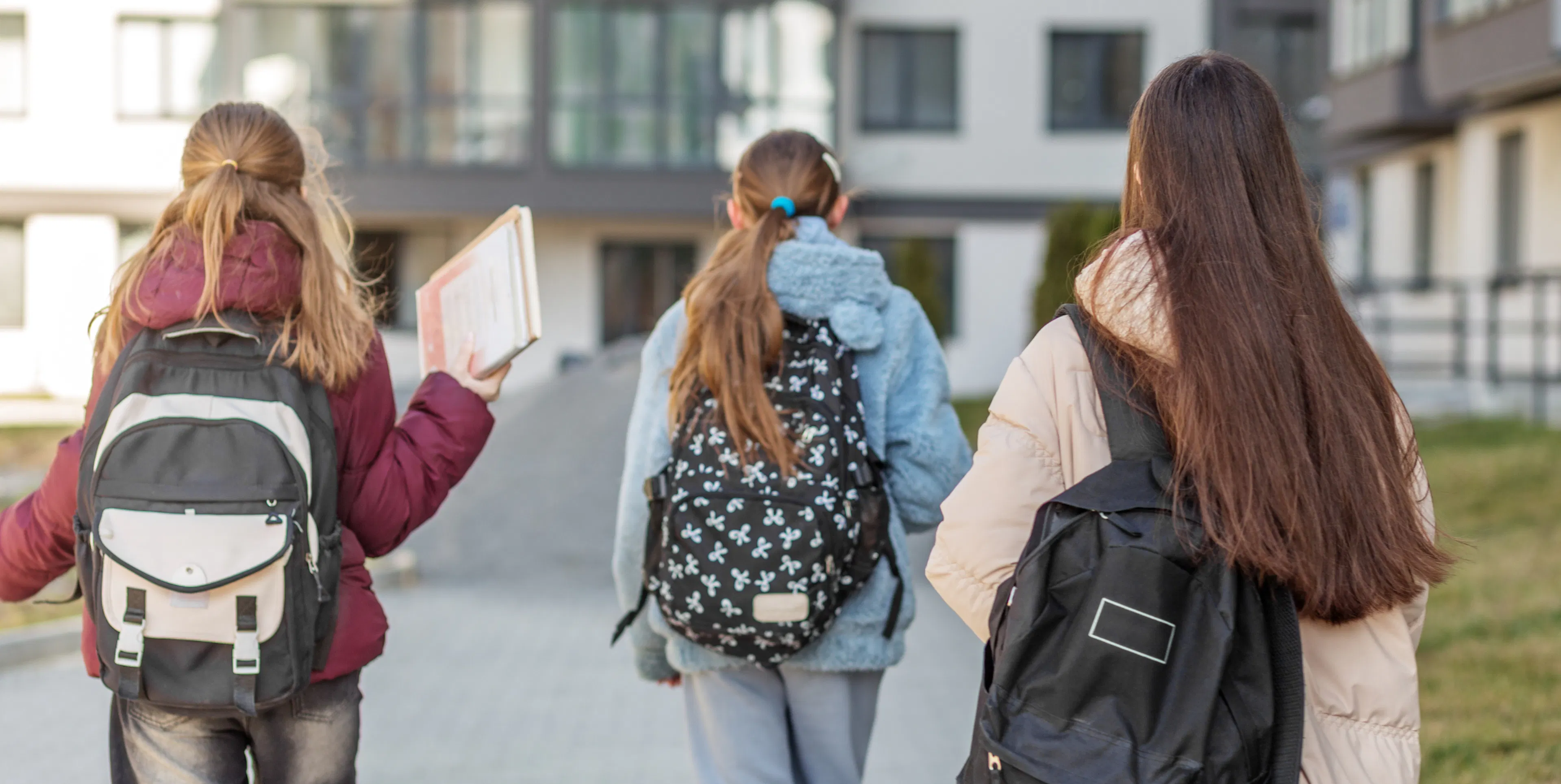 Teenage girls wearing back packs walking back to school