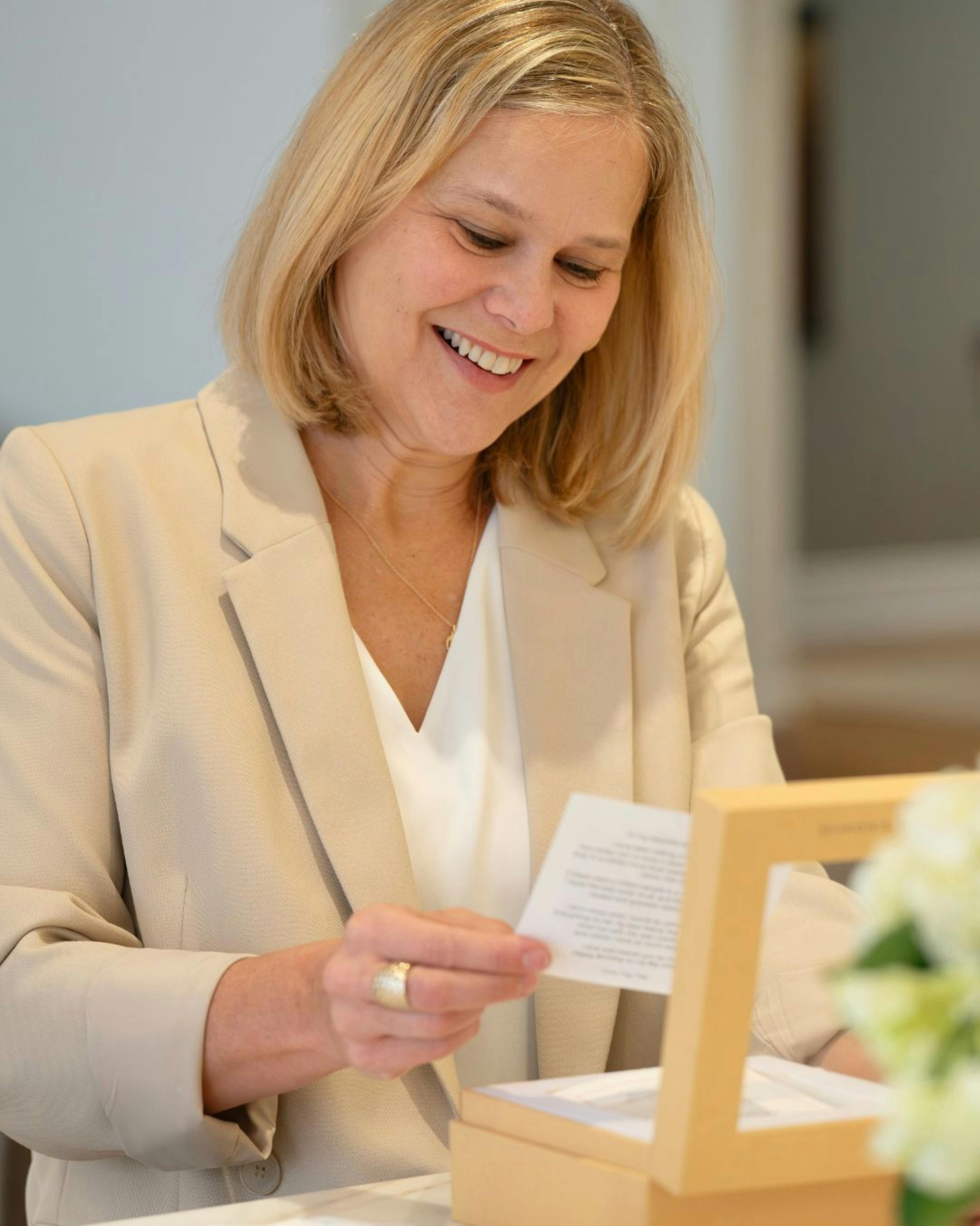 Woman opening a Woxbox gift and reading her words of kindness messages