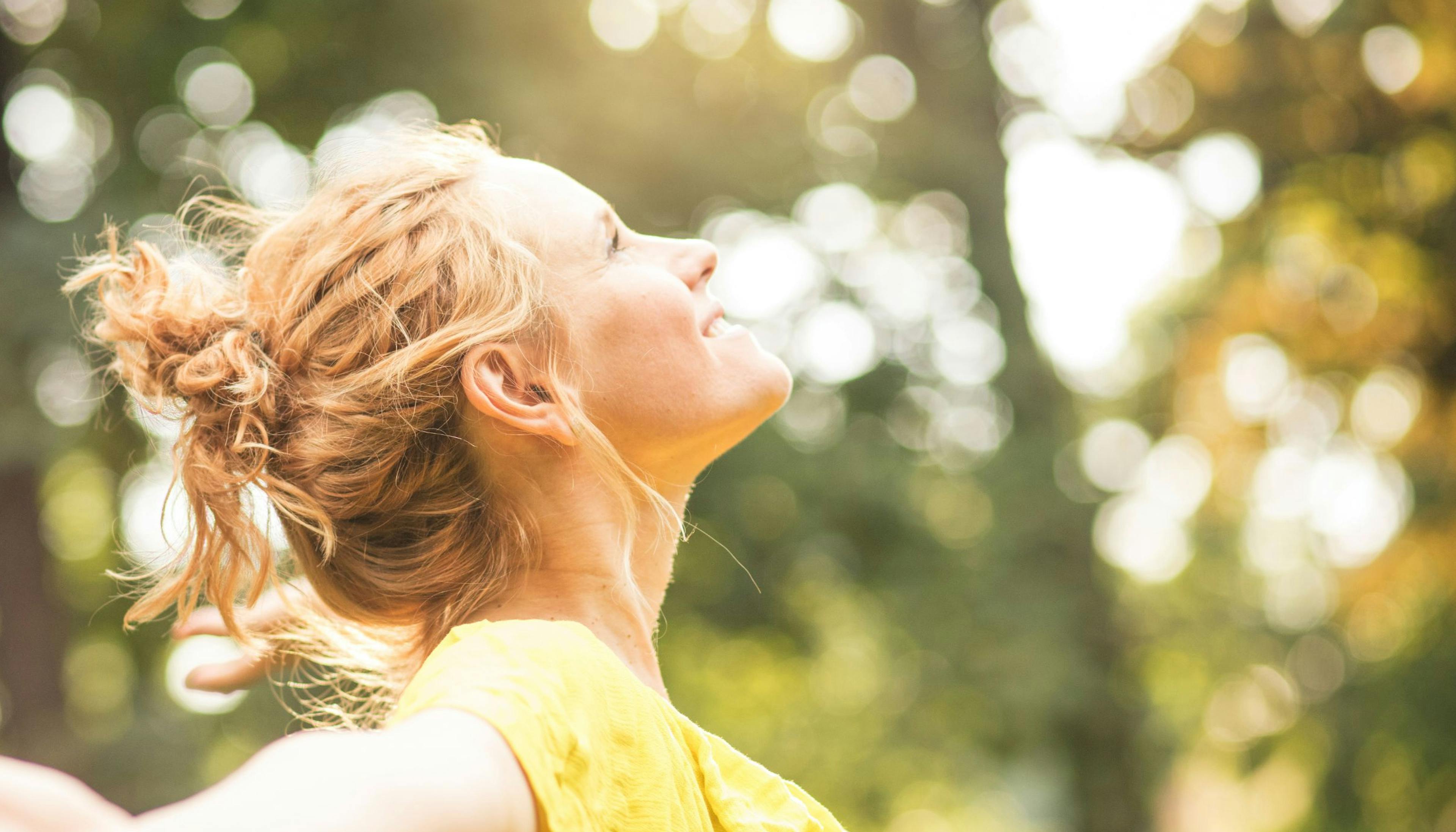 Woman smiling and finding joy with the sun on her face