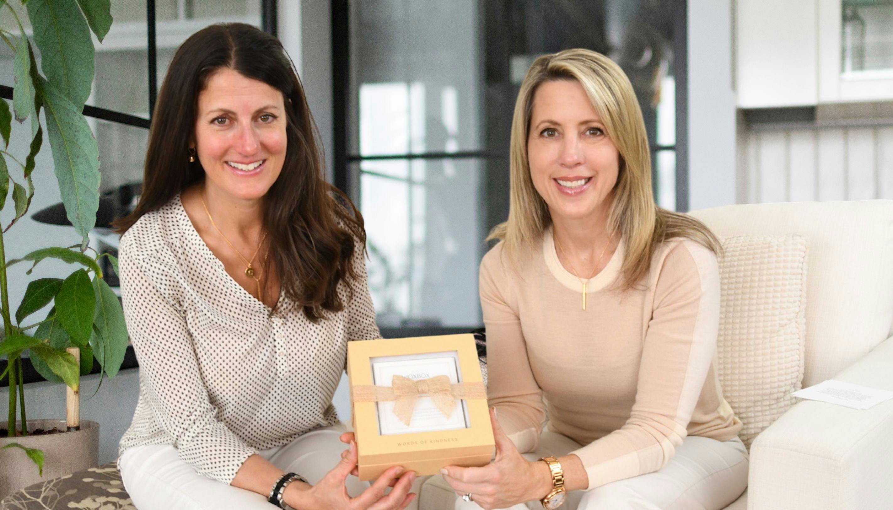 Cindy Iatan and Carey Kirchmair, co-founders of Woxbox, holding a Woxbox Words of Kindness Gift