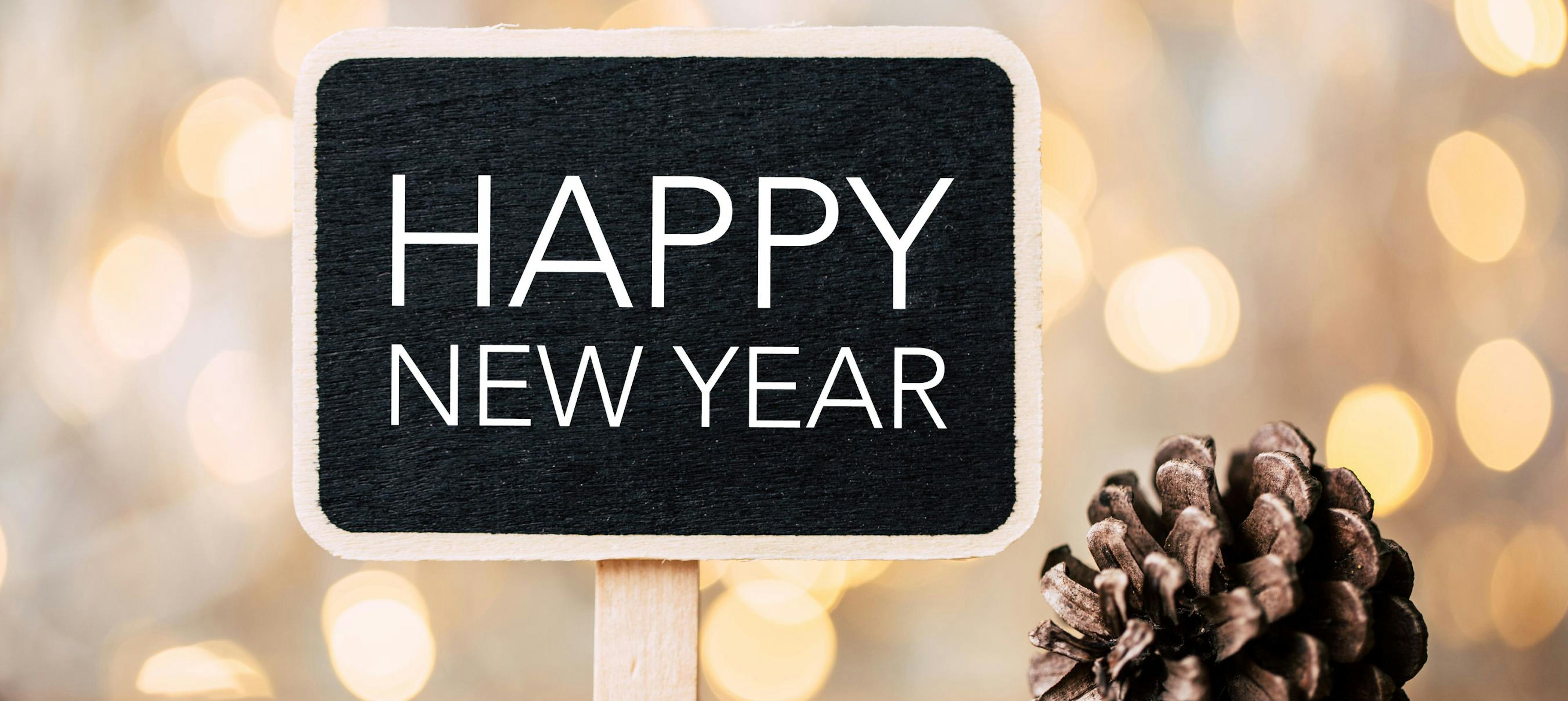 Happy New Year sign on table with twinkly lights behind it