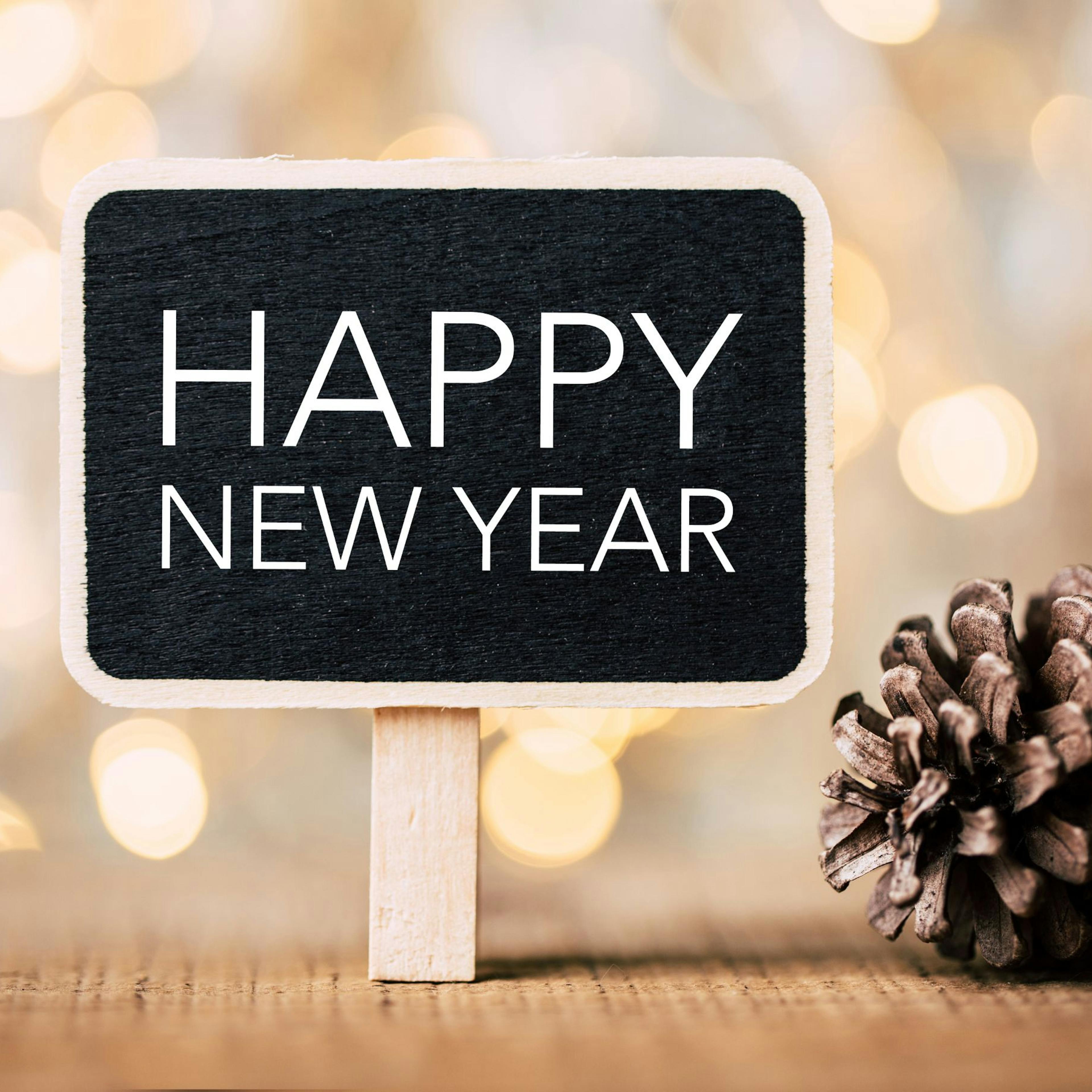 Happy New Year sign on table with twinkly lights behind it