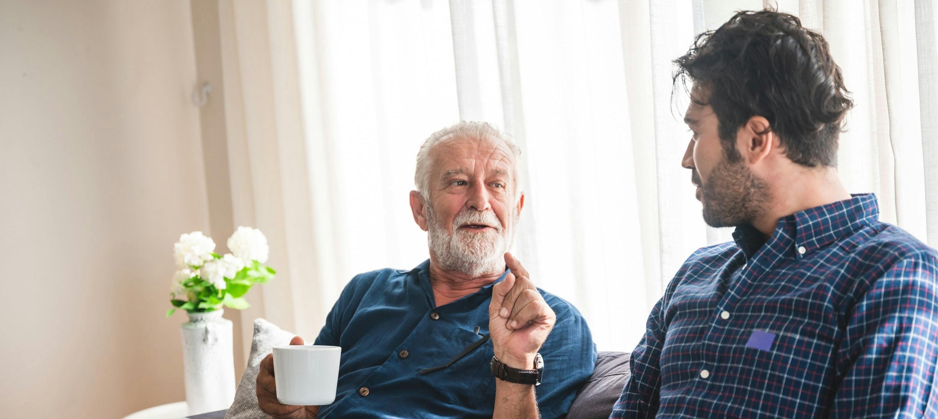 Adult child having heartfelt conversation with elderly parent in cozy home setting, representing meaningful family connections and gratitude