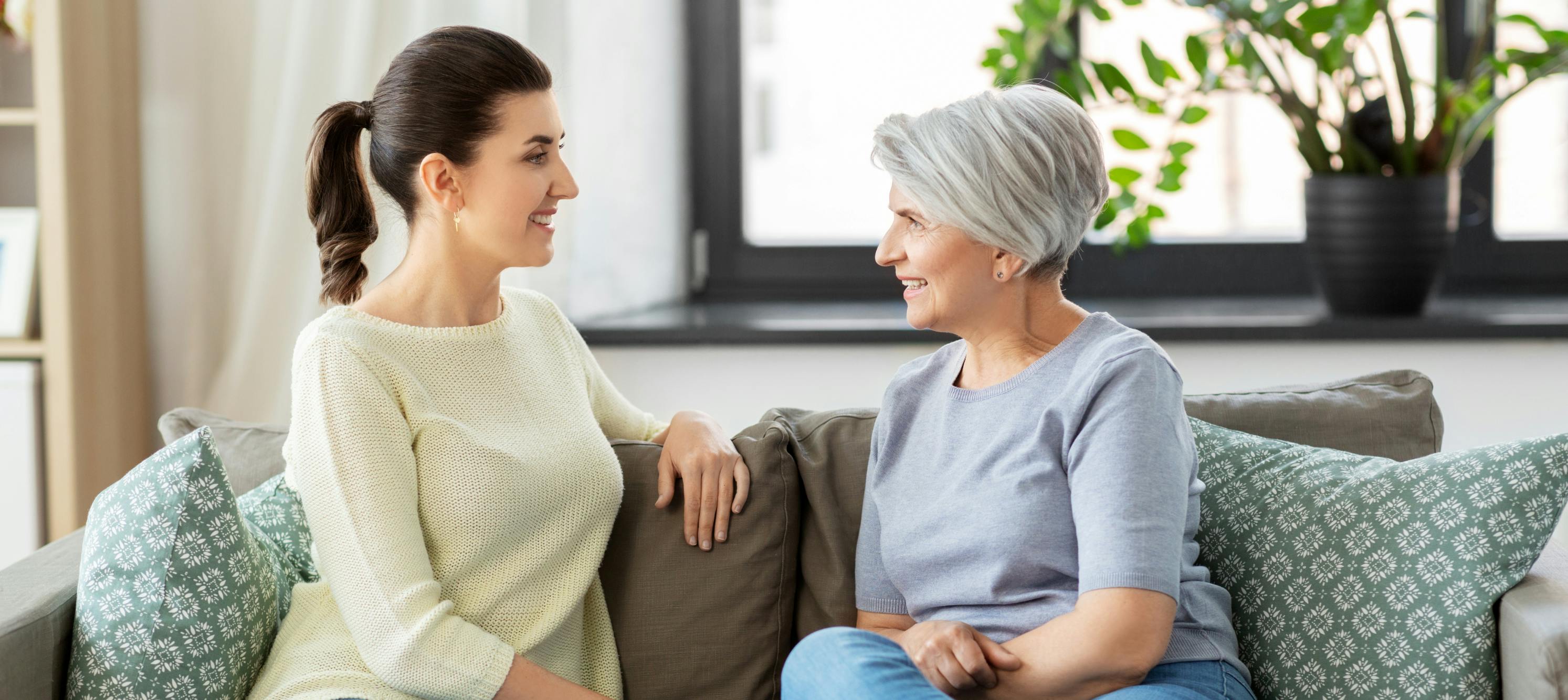 Adult child having heartfelt conversation with elderly parent in cozy home setting, representing meaningful family connections and gratitude