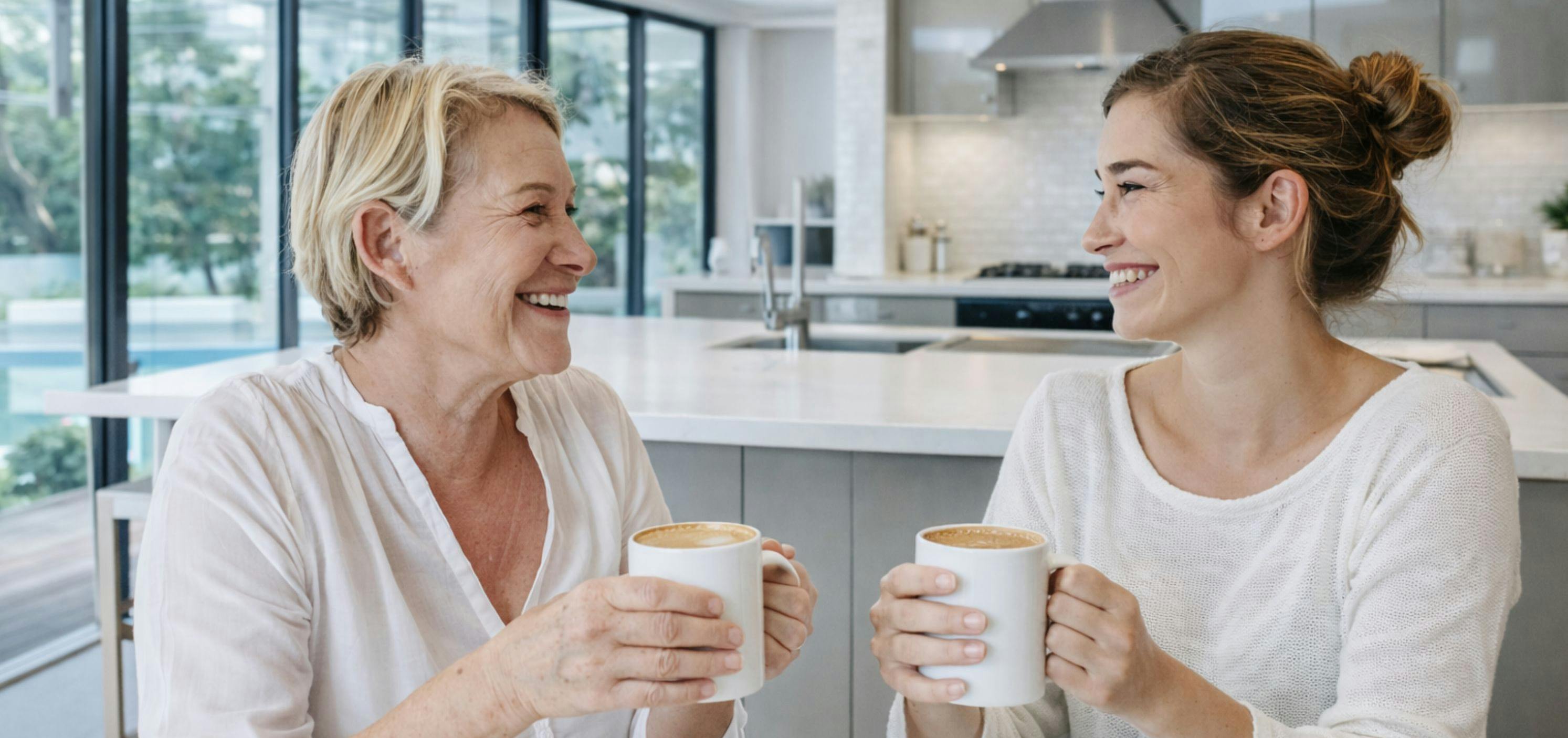 Mother and adult daughter having coffee together and being supportive of each other