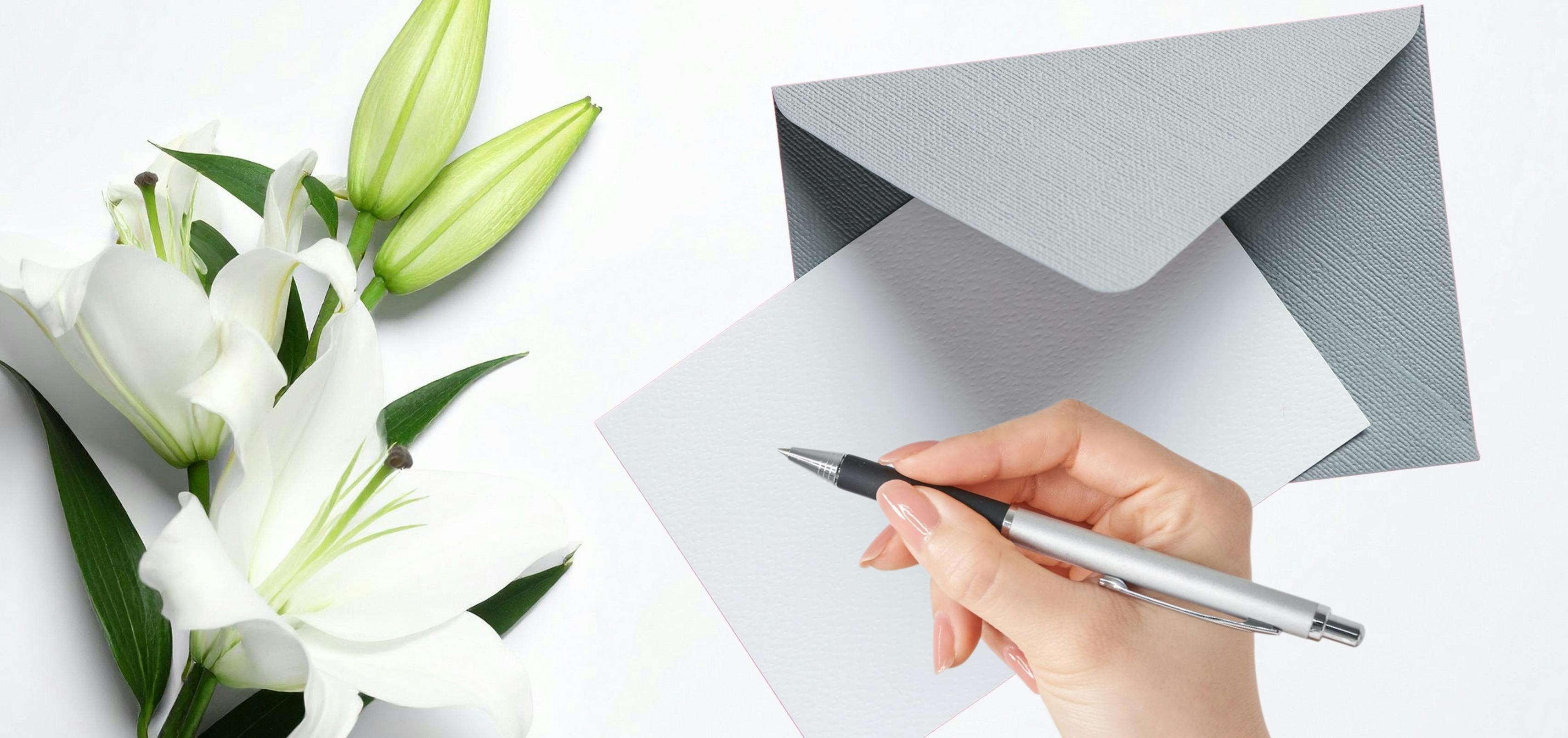 Close-up of blank condolence card with pen and fresh flowers on a table