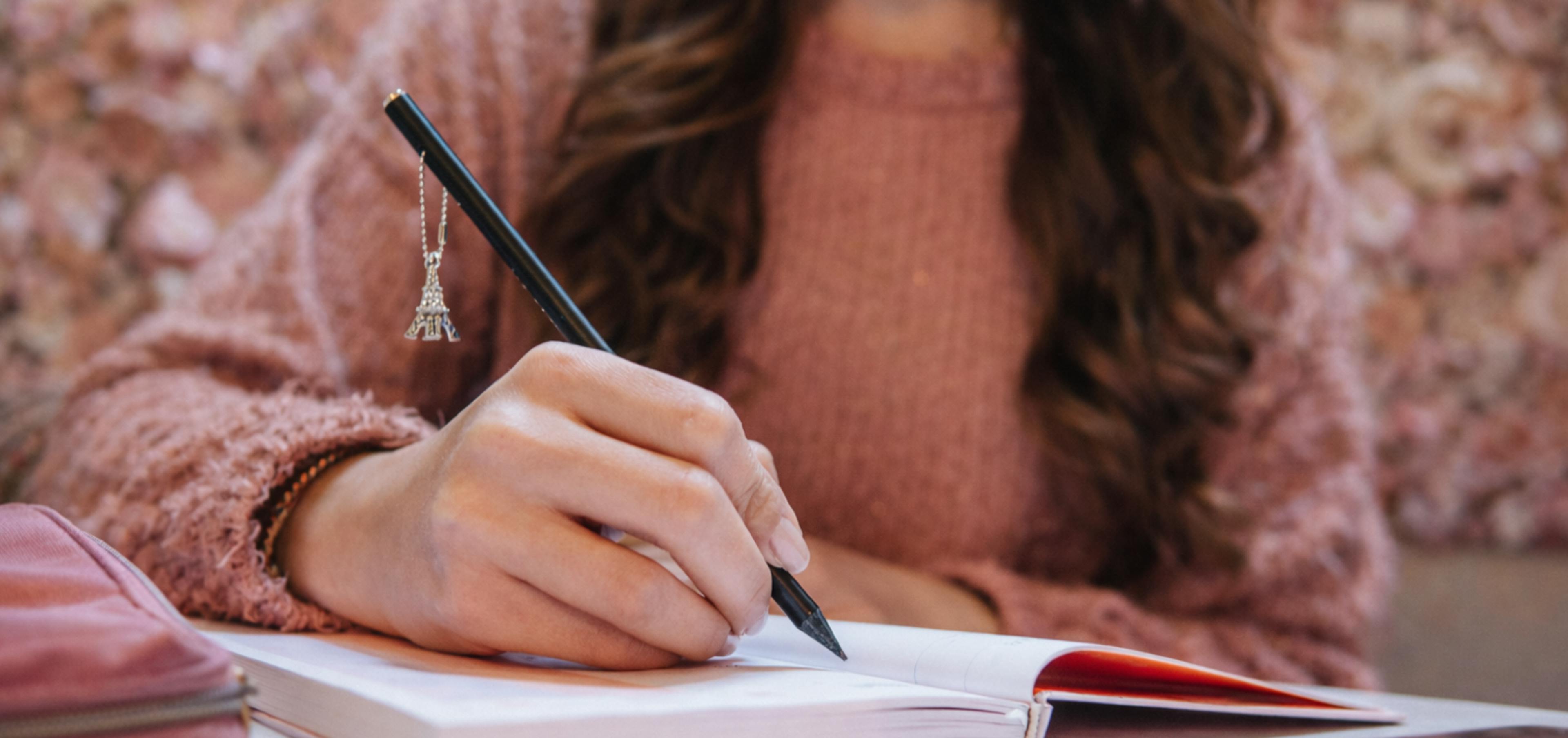 Person writing heartfelt personal message in card with pen and thoughtful expression