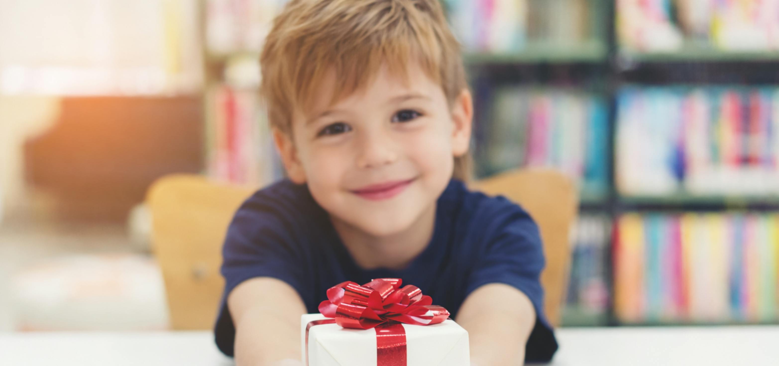 Young student handing his teacher a wrapper teacher gift