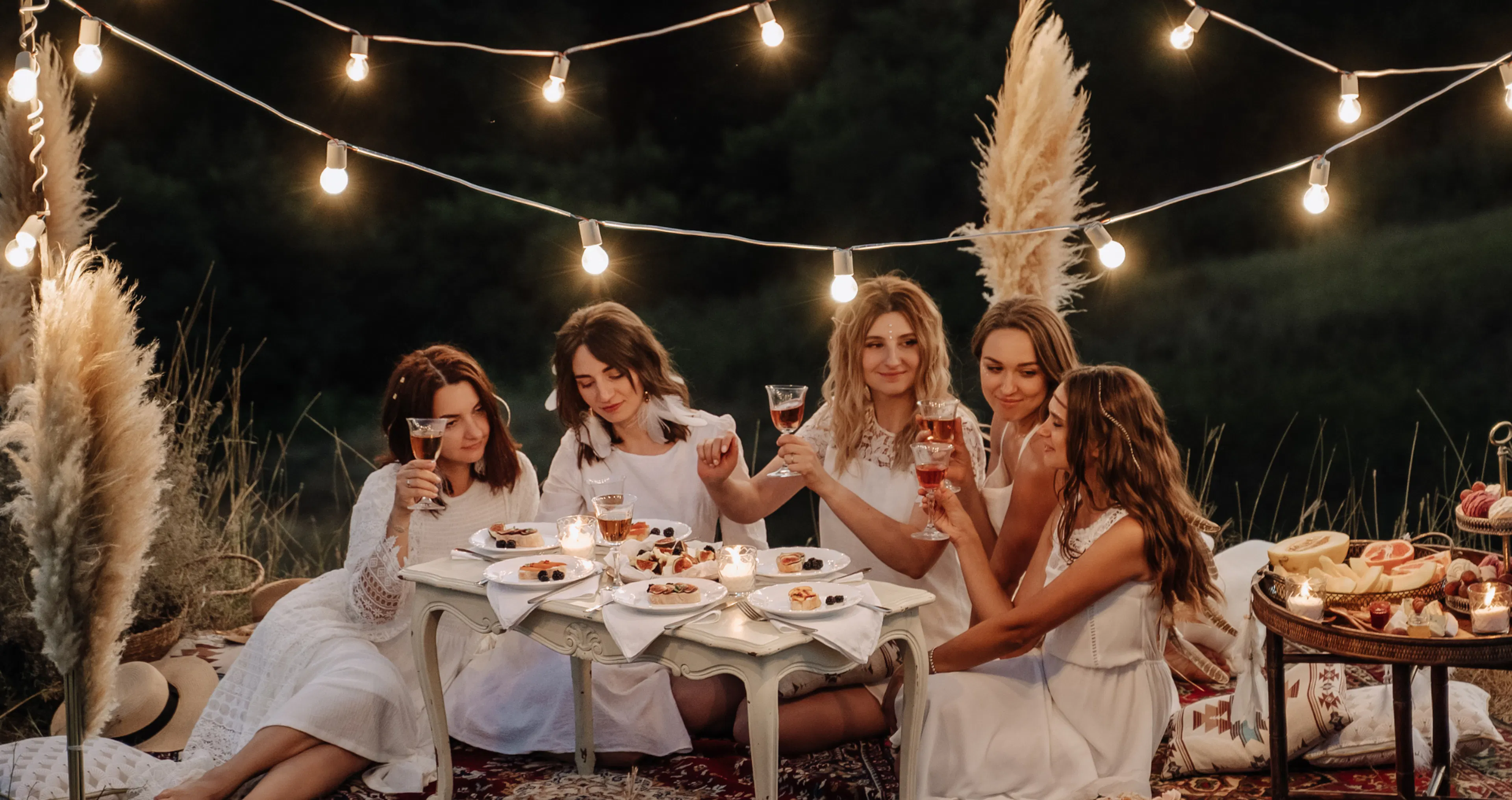 Friends gathered at an engagement party celebrating in a cozy setting with champagne and twinkle lights