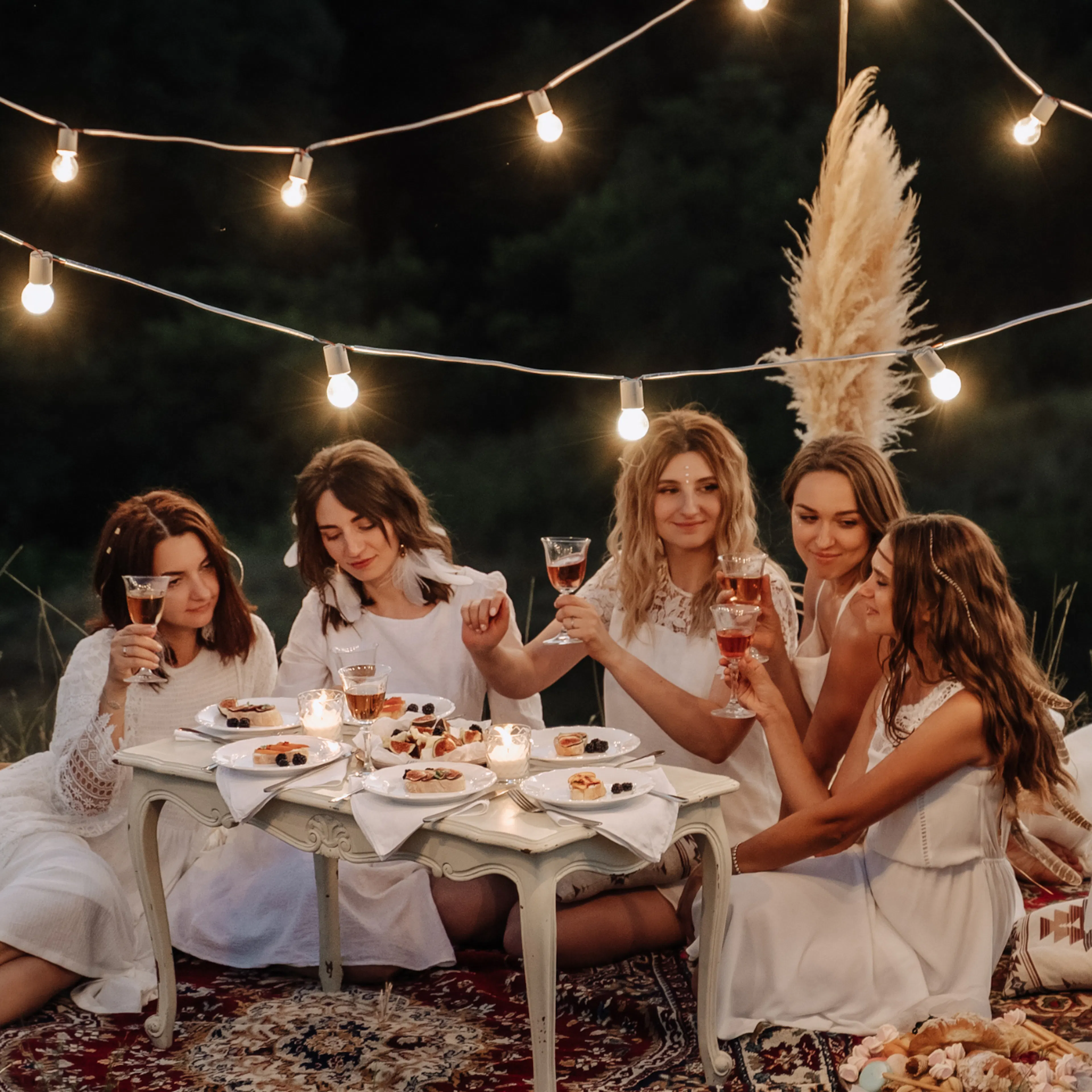 Friends gathered at an engagement party celebrating in a cozy setting with champagne and twinkle lights
