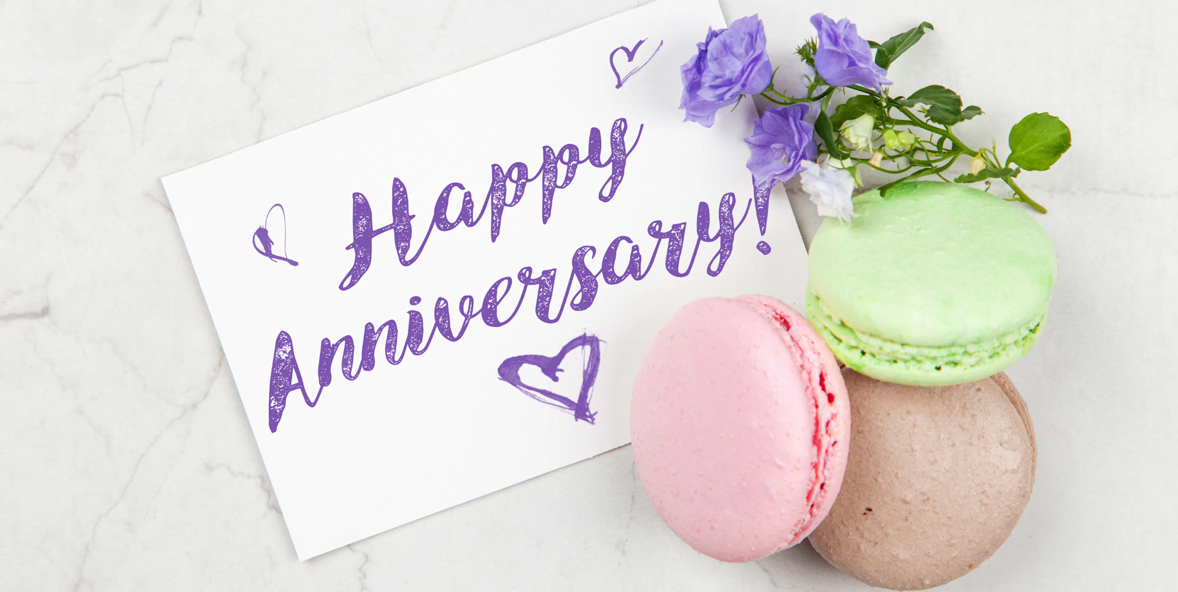 Happy anniversary card on display with french macarons, representing a thoughtful anniversary gift