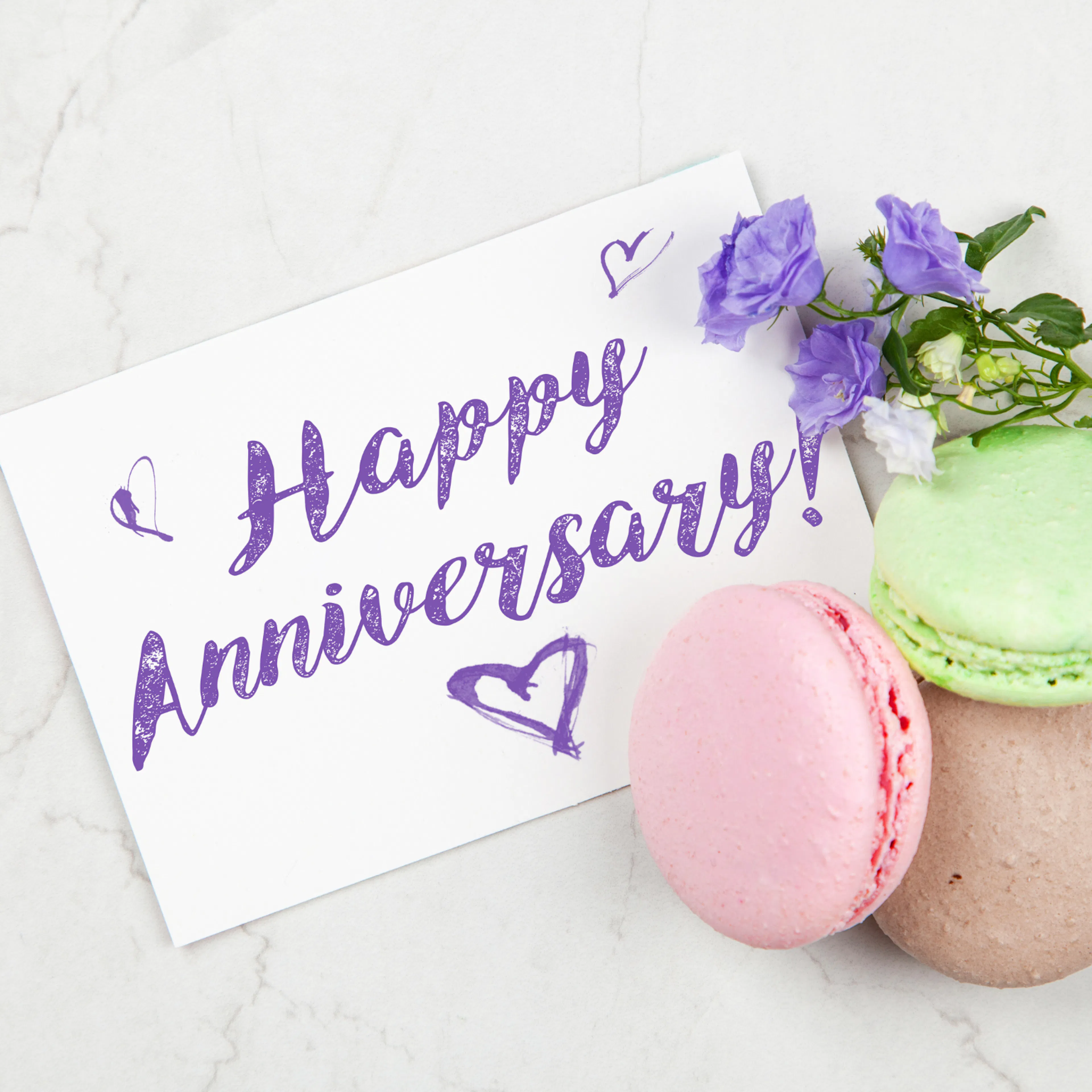 Happy anniversary card on display with french macarons, representing a thoughtful anniversary gift