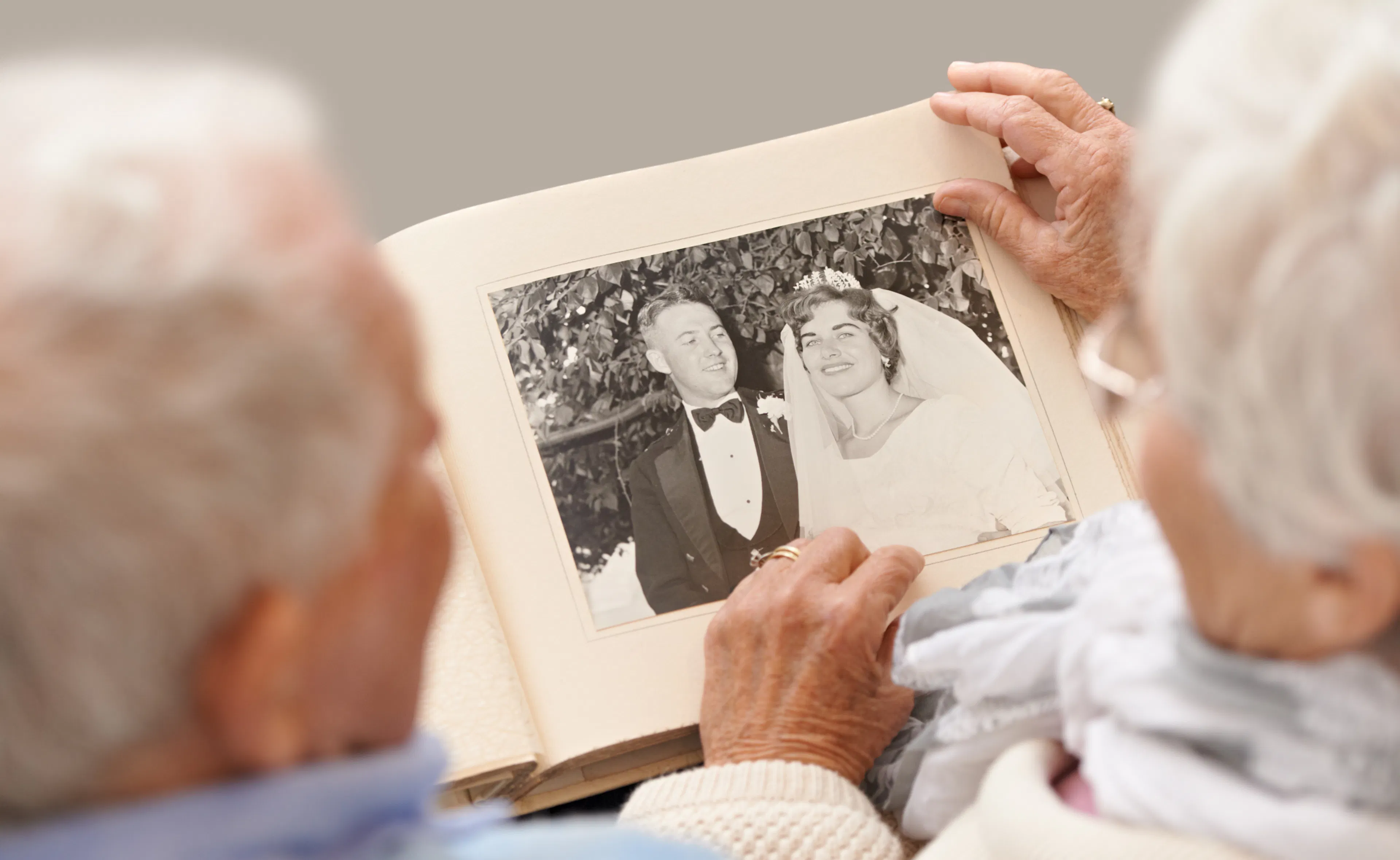 A couple sitting together looking at a collection of old wedding photos