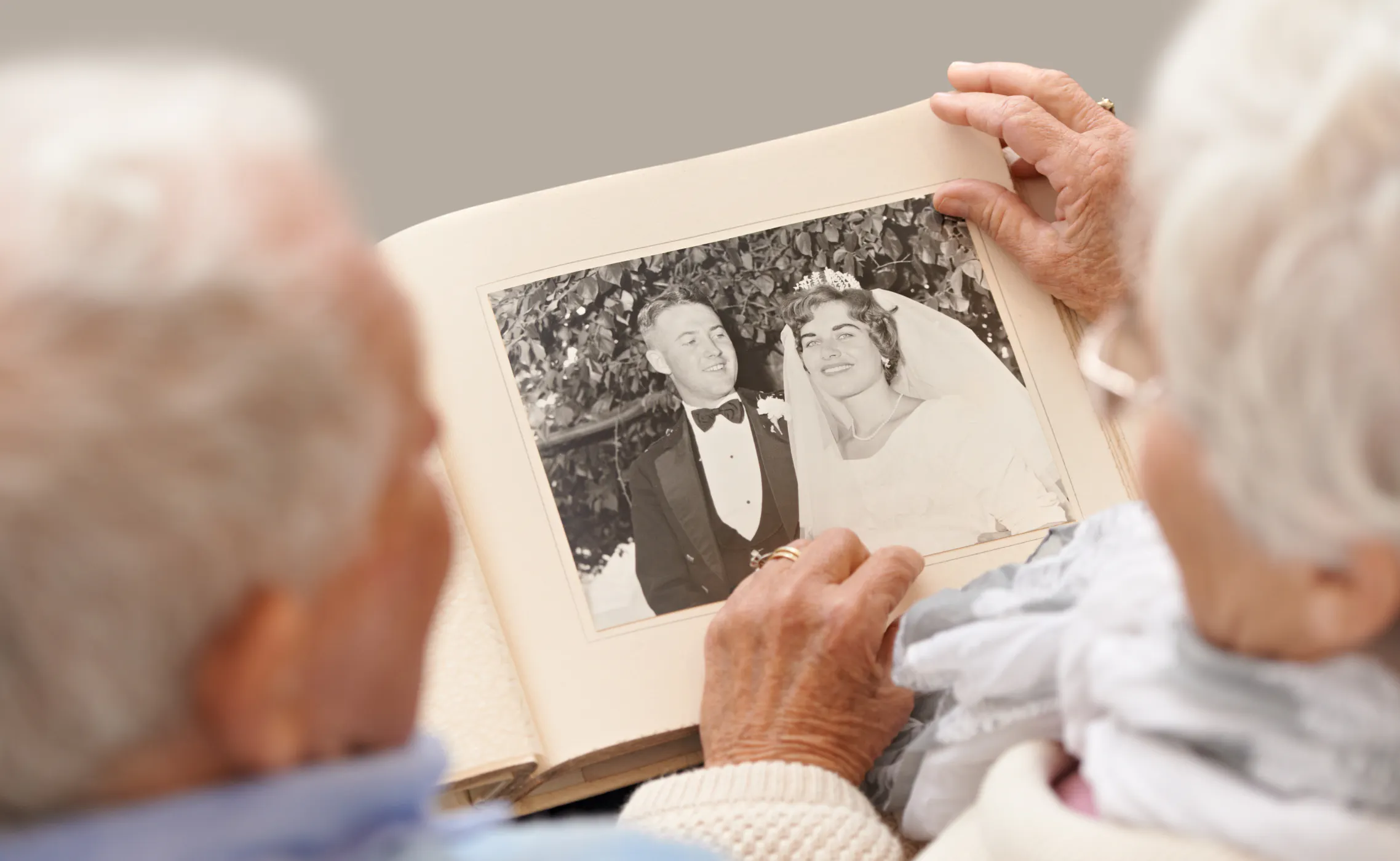 A couple sitting together looking at a collection of old wedding photos