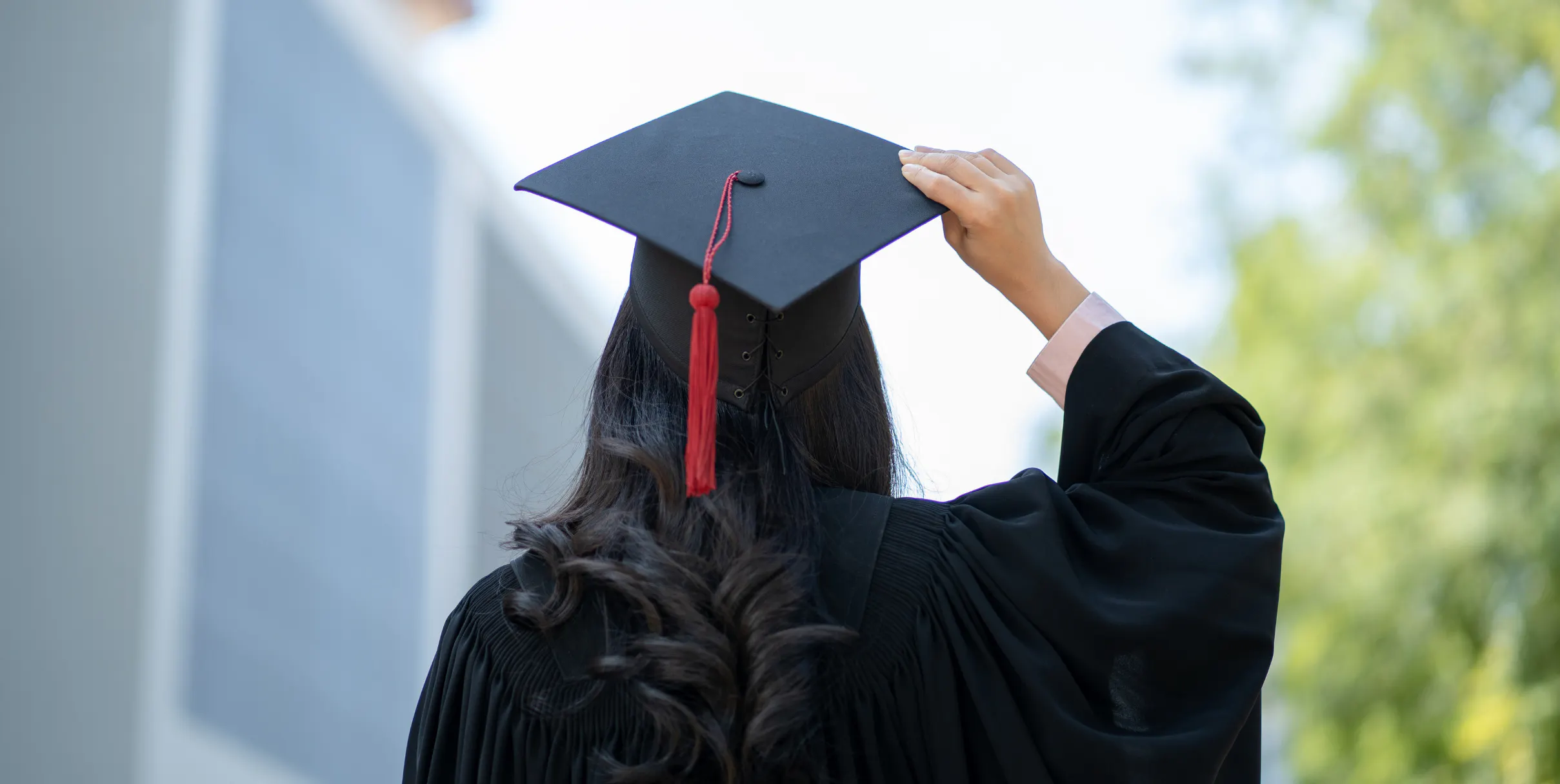 Grad in cap and gown looking toward the horizon as she celebrates graduation day