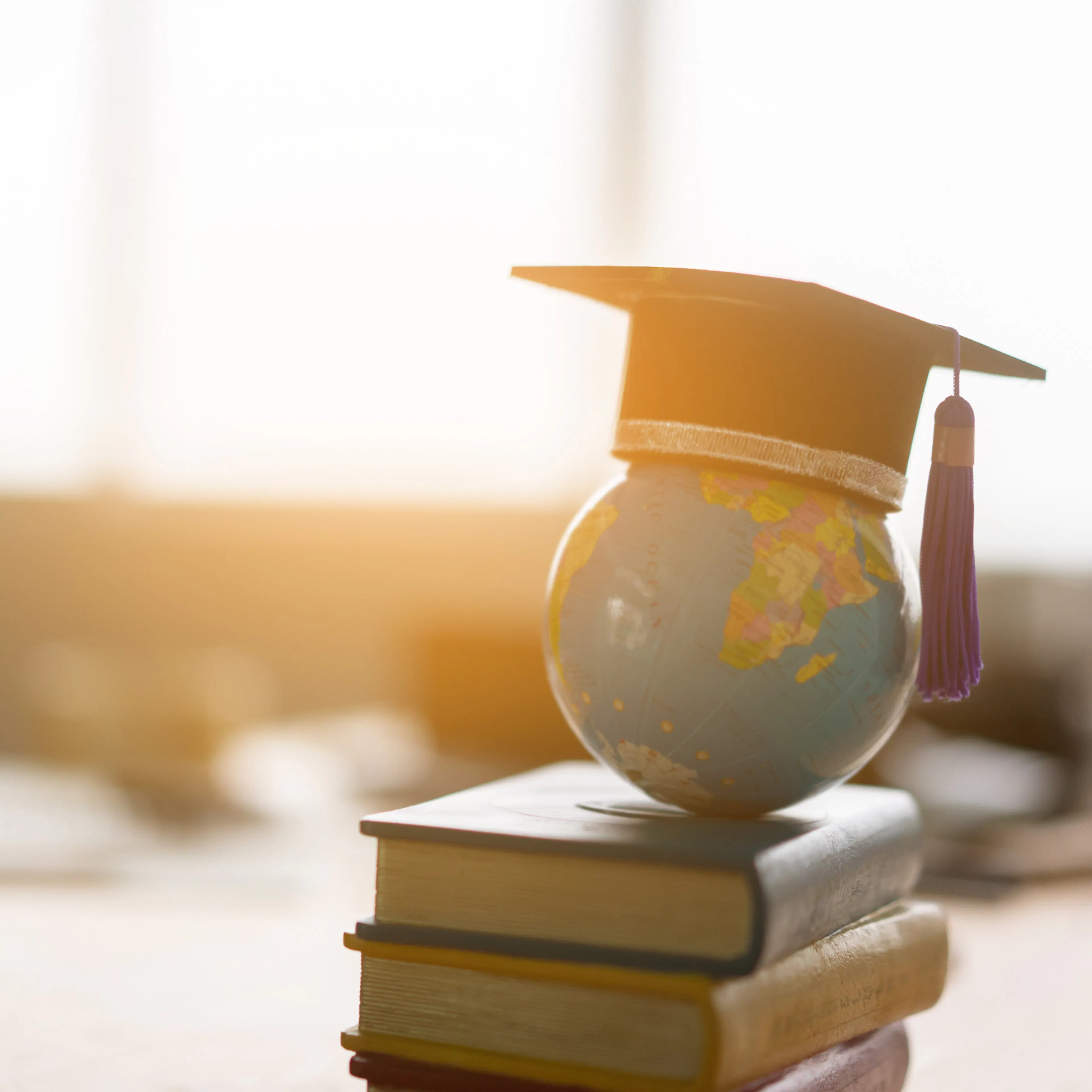 Textbooks and world globe on a desk wtih a graduation cap, signifying the exciting possibilities ahead for a recent graduate