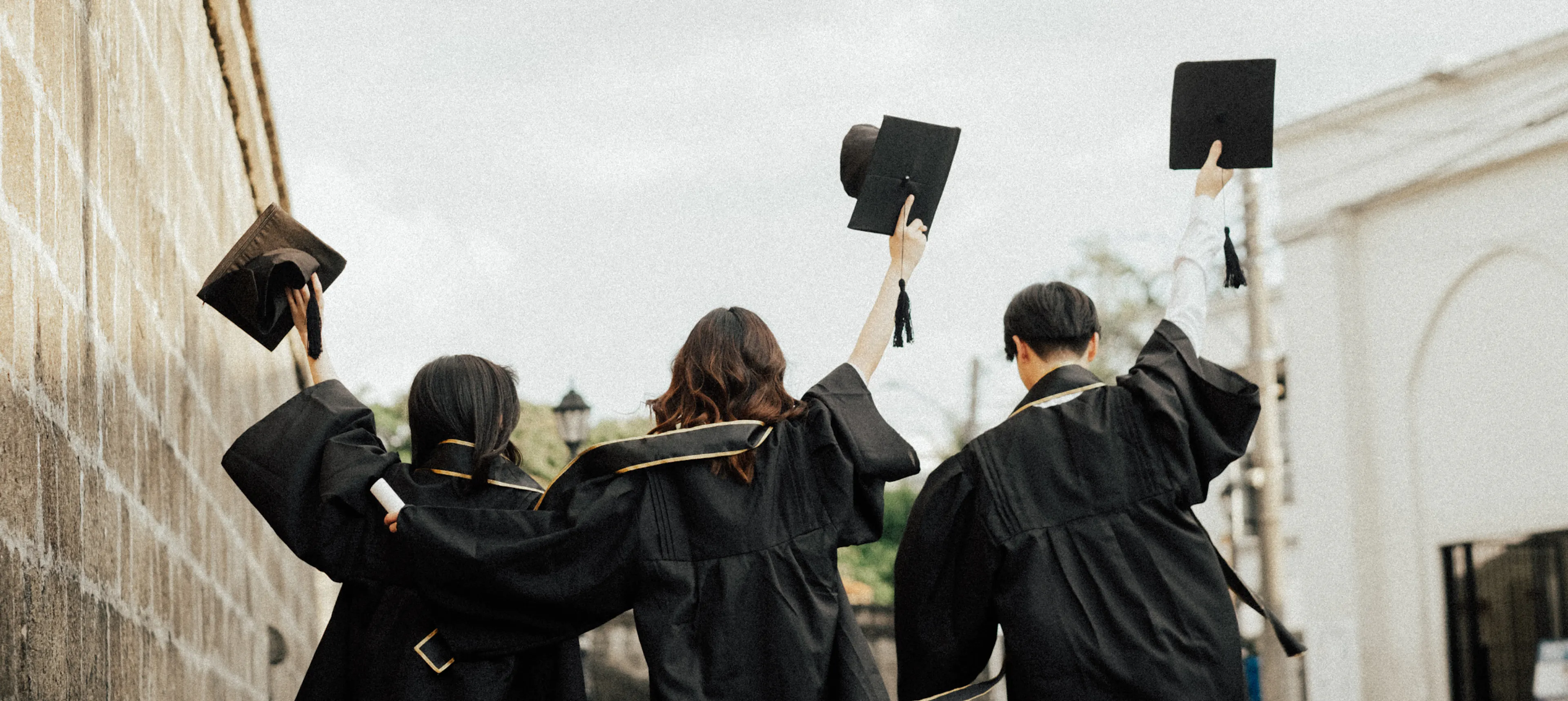 Grads in caps and gowns celebrating on graduation day