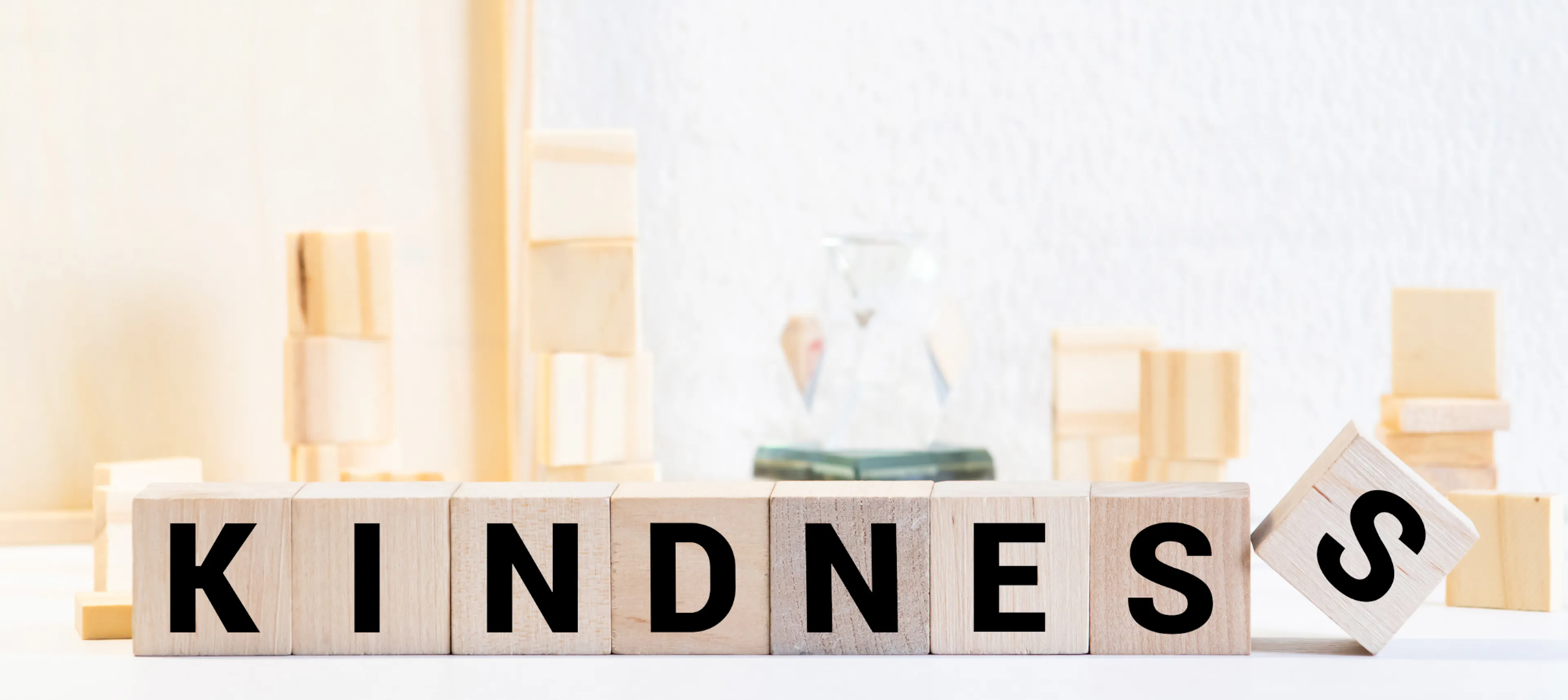 The word "kindness" spelled in blocks with science equipment displayed behind, representing the science of kindness