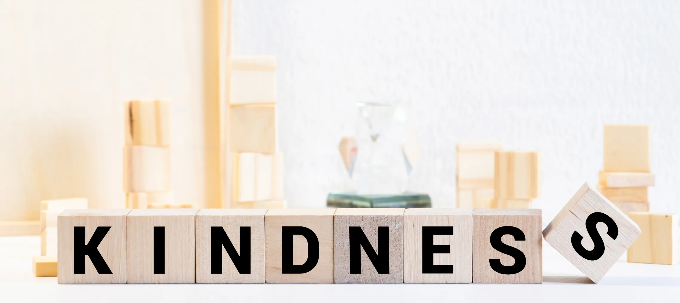The word "kindness" spelled in blocks with science equipment displayed behind, representing the science of kindness