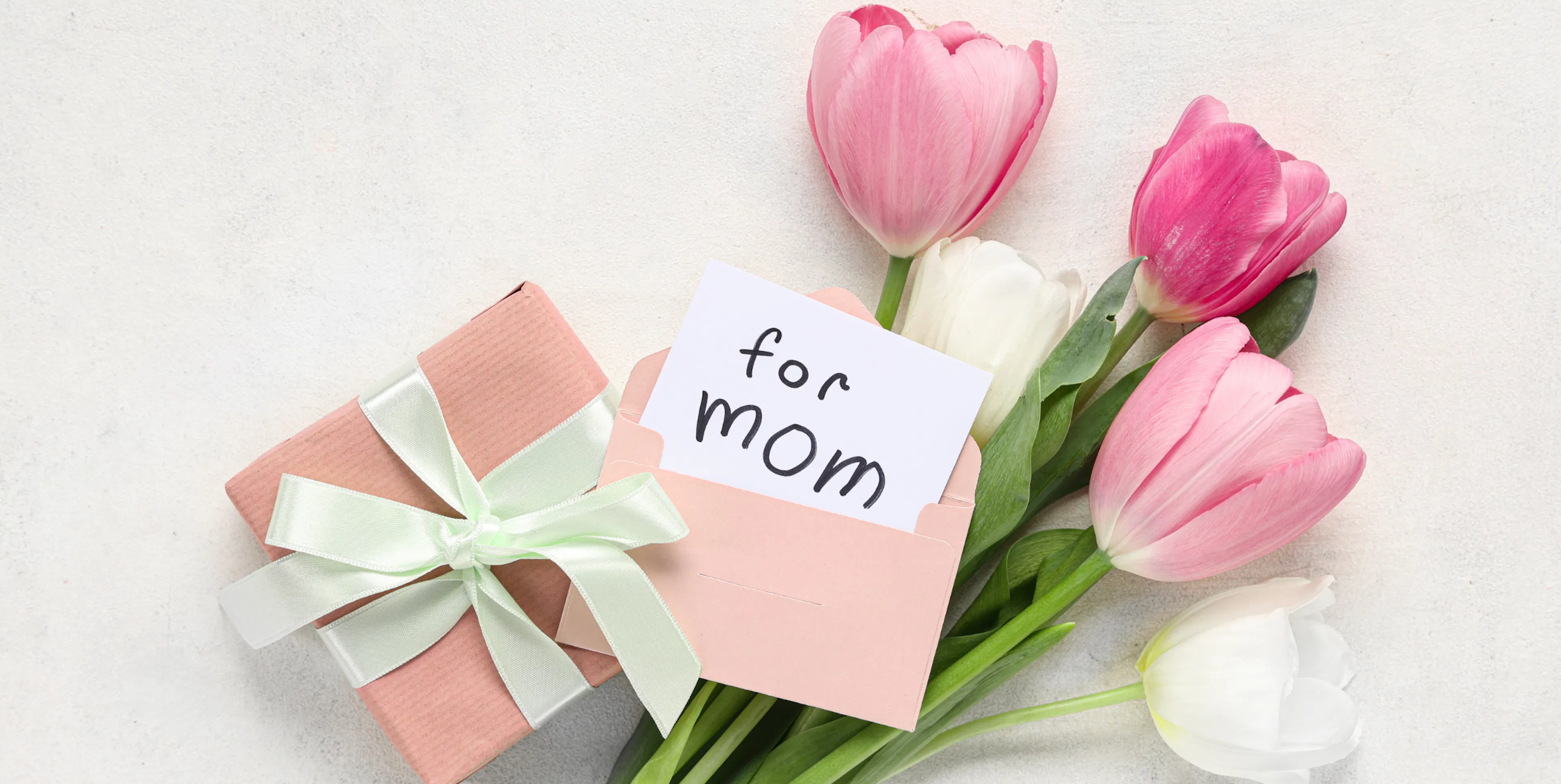 Pink and white tulips beside a wrapped gift and a card that reads "for Mom"