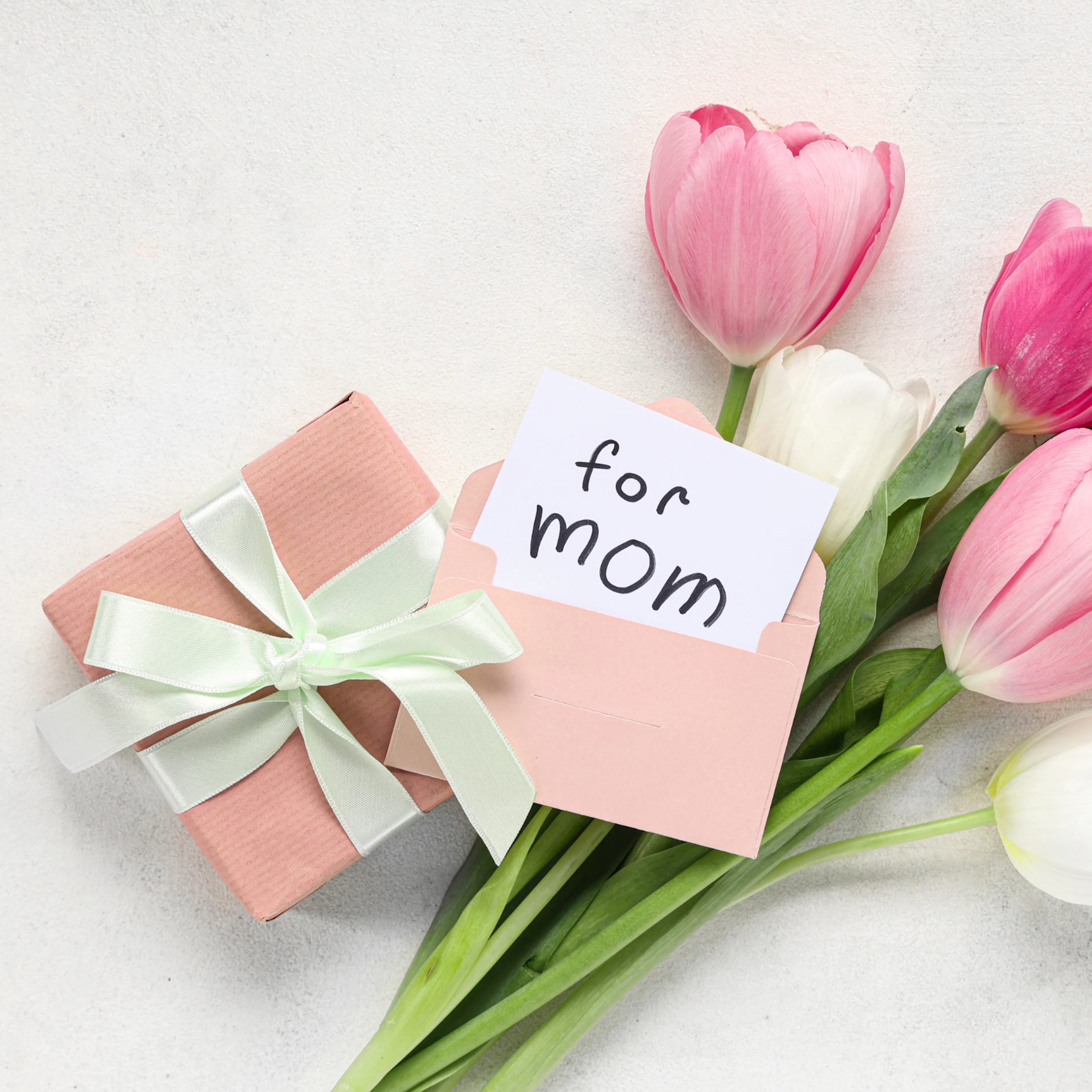 Pink and white tulips beside a wrapped gift and a card that reads "for Mom"