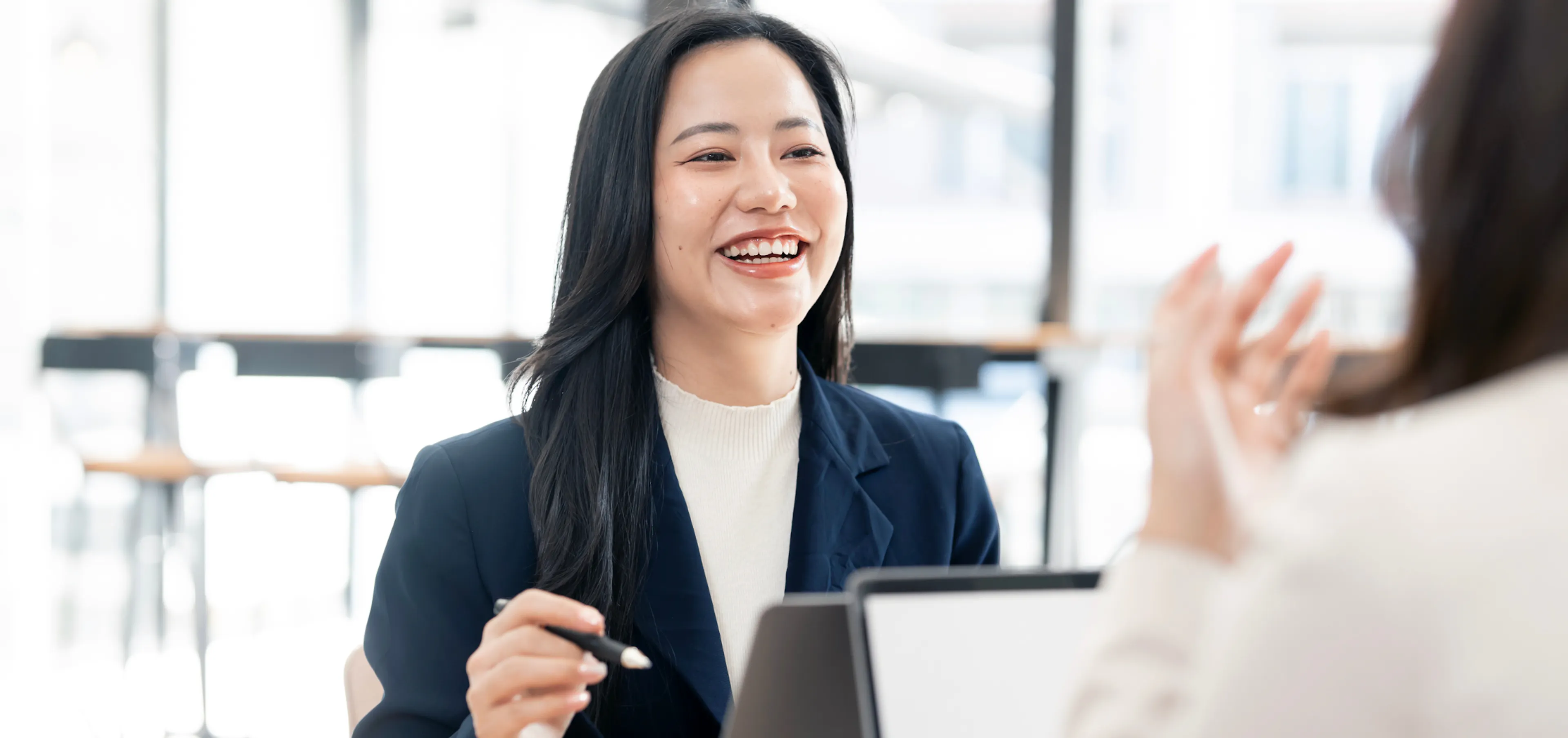 Professional woman laughing as a colleague recognizes her contribution during a team meeting