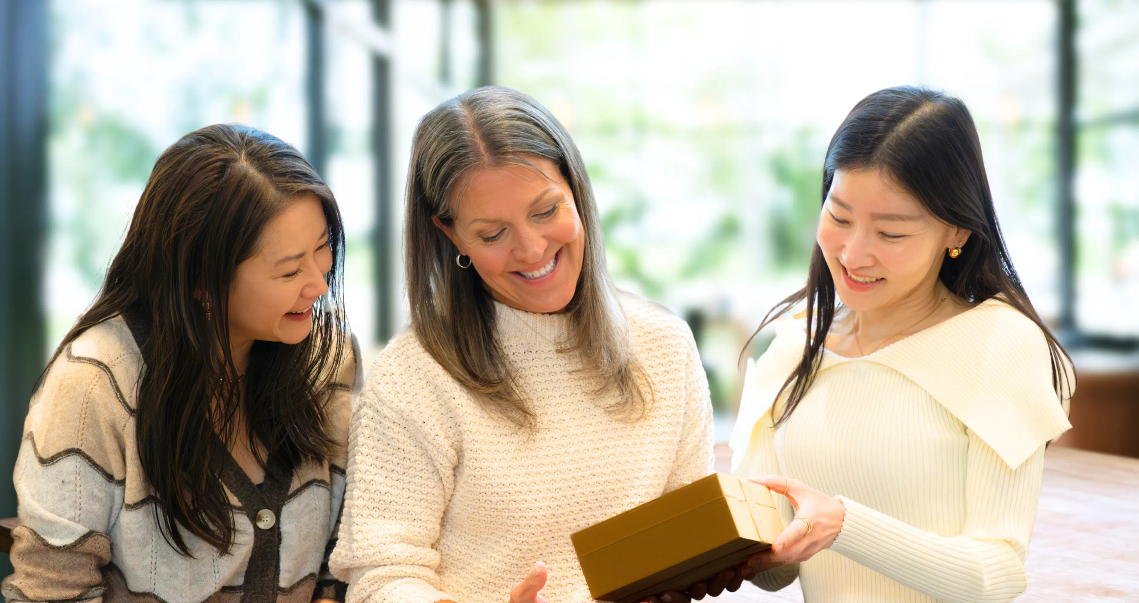Three coworkers smiling as they admire a Woxbox gift of messages from the team