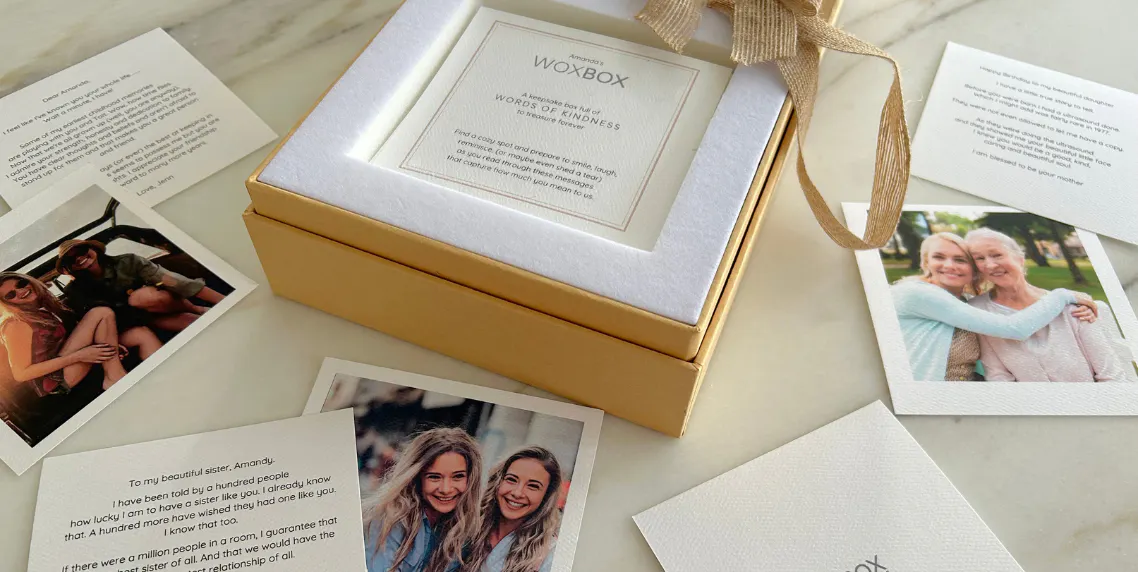 Printed note cards and photos on a counter with an open Woxbox, as part of a group gift