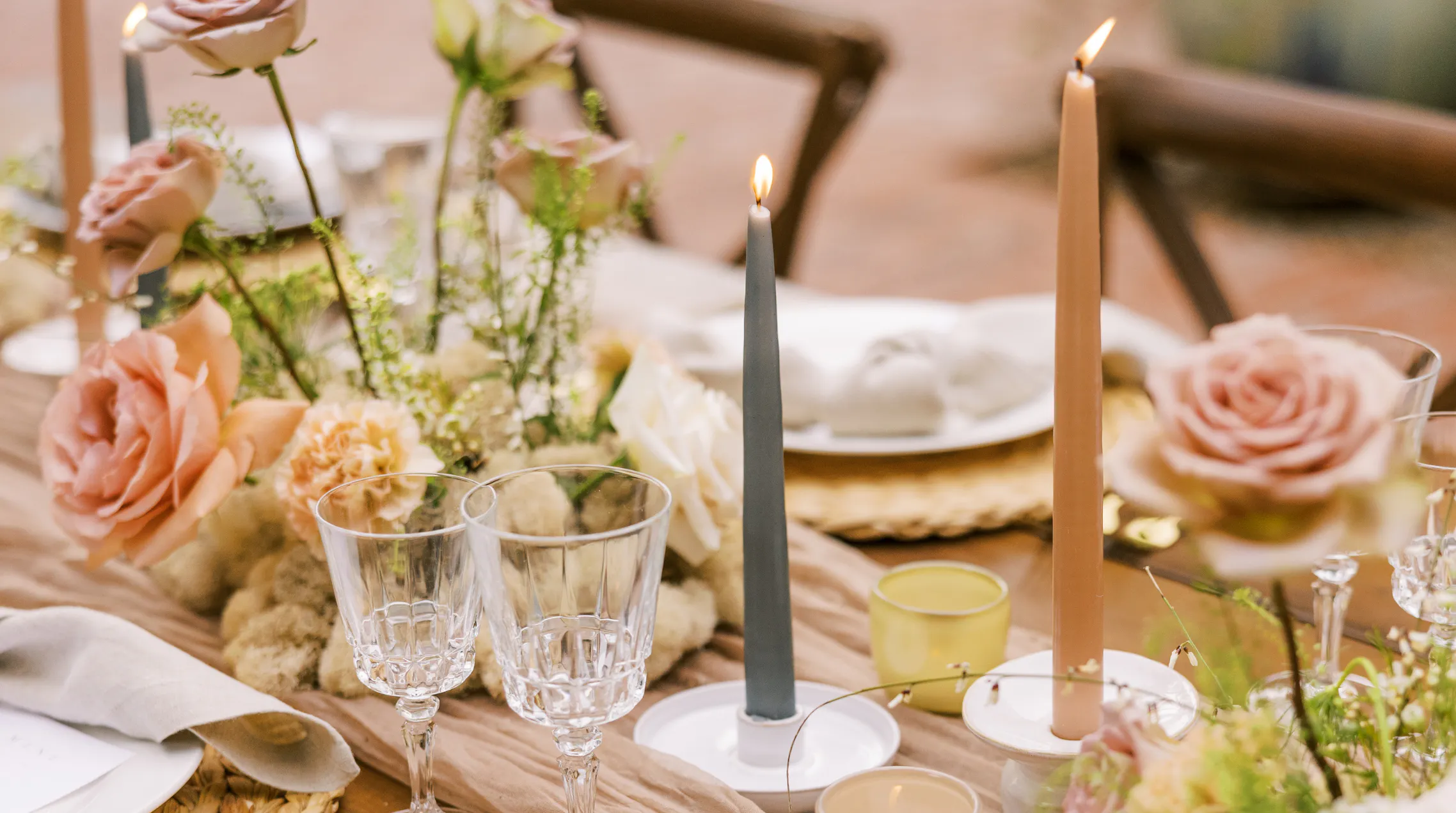 Outdoor table with flowers, candles and wine set up for for summer gathering