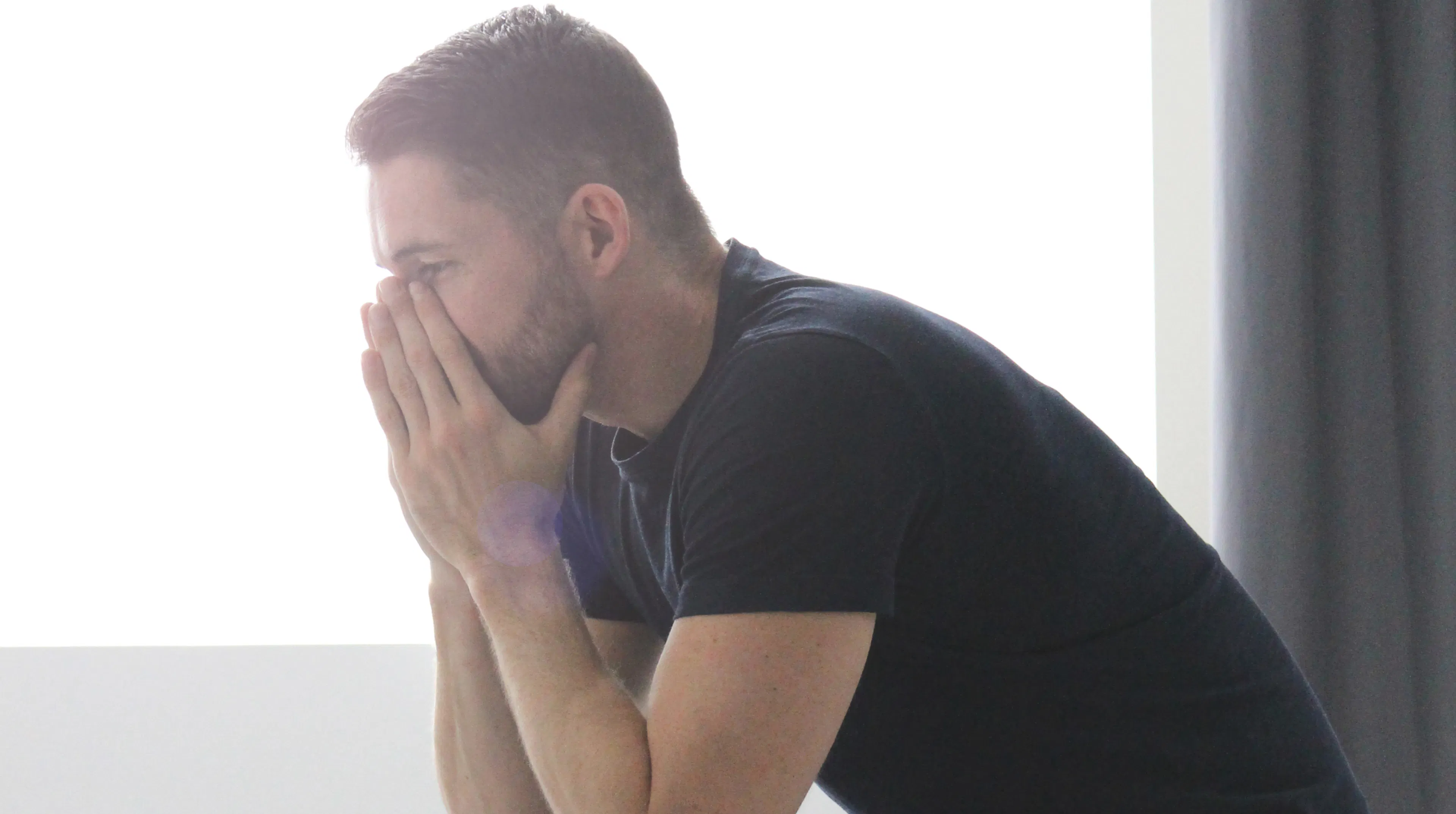 Man struggling with stress, sitting with hands covering his mouth