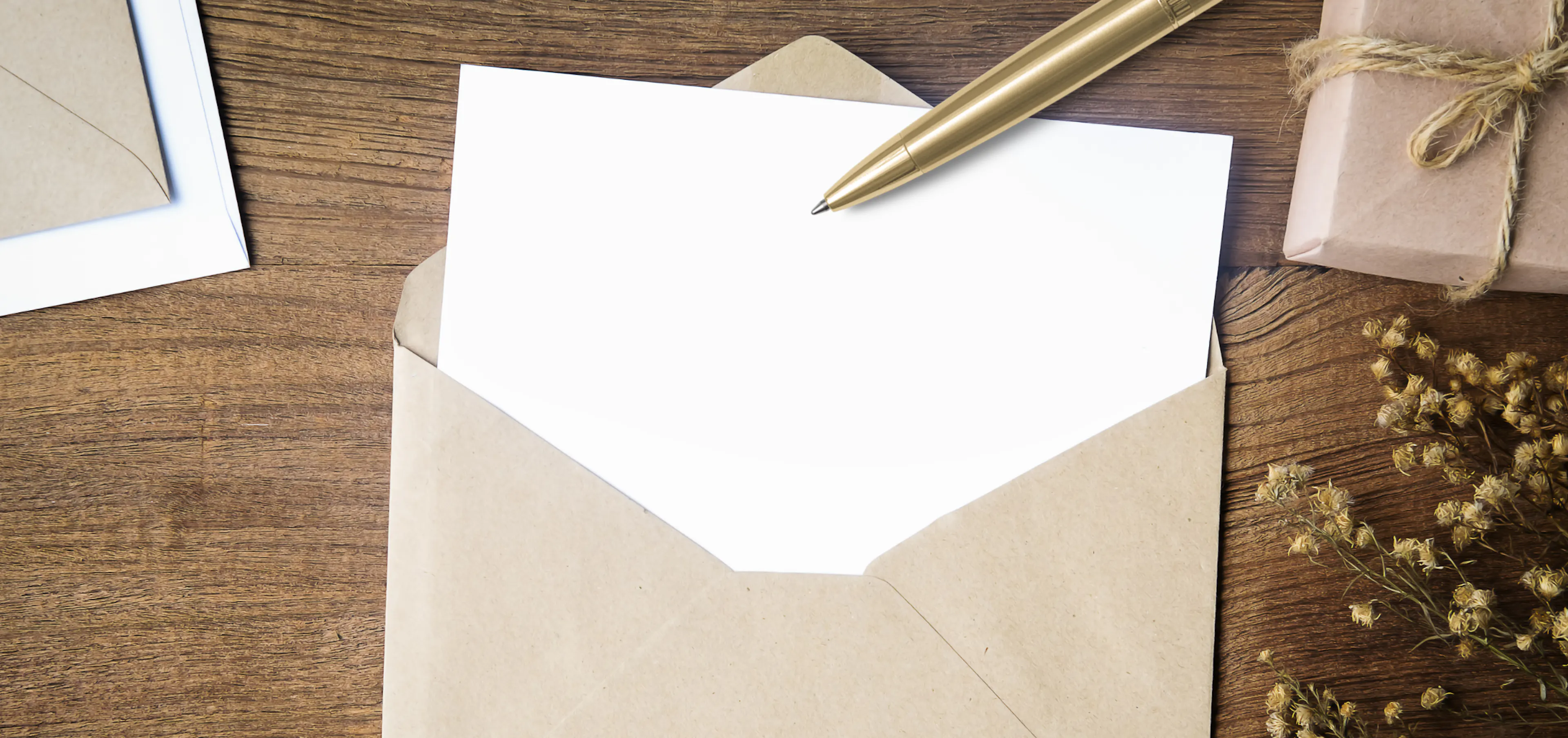 Blank card tucked into a kraft envelope with a gold pen on a wooden table, waiting for a new chapter message