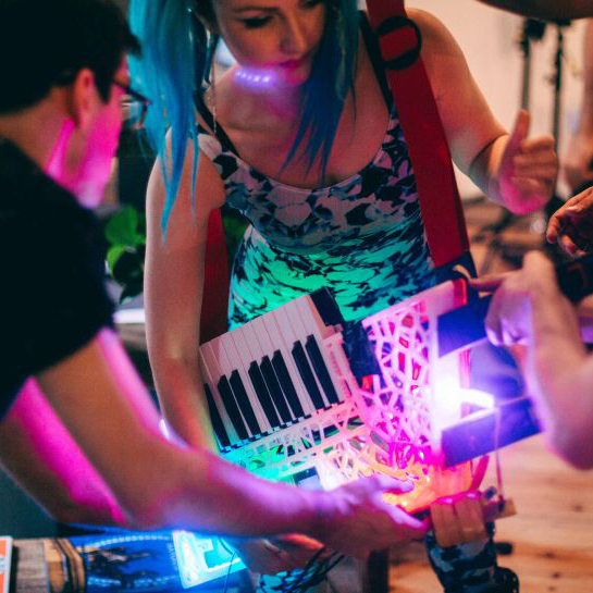 Blade, a double necked keytar, held by Amy from them&us, Sam Wray providing support to hold it up.