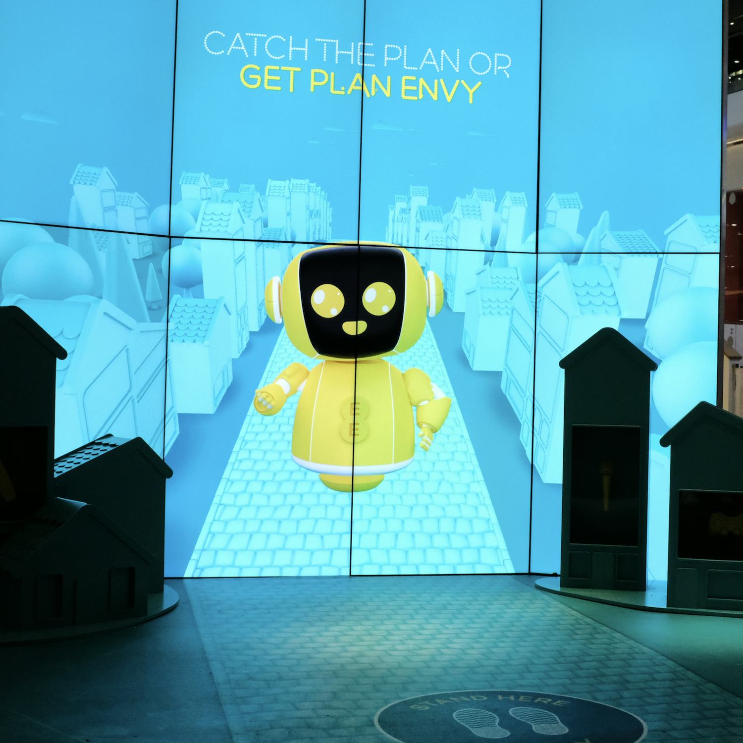 Yellow robot on 8 large screens in an EE store