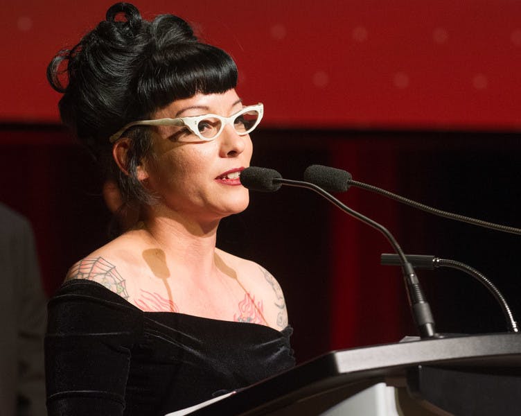 A woman wearing a gown stands at a podium