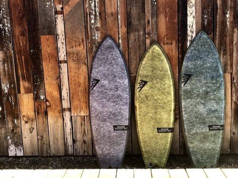 Three seaside boards lined up against a wooden wall.