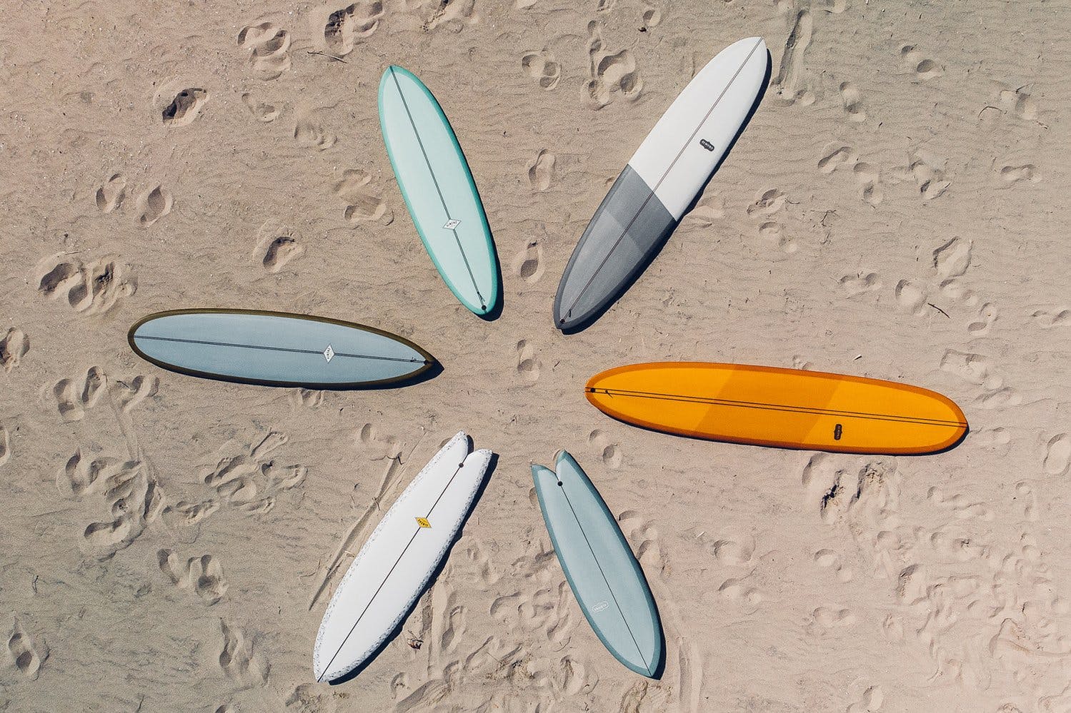 A ring of multicolored almond surfboards on sand.