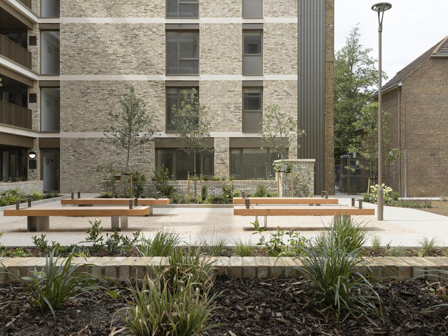 A ground level view of a block of apartments in the sunshine.