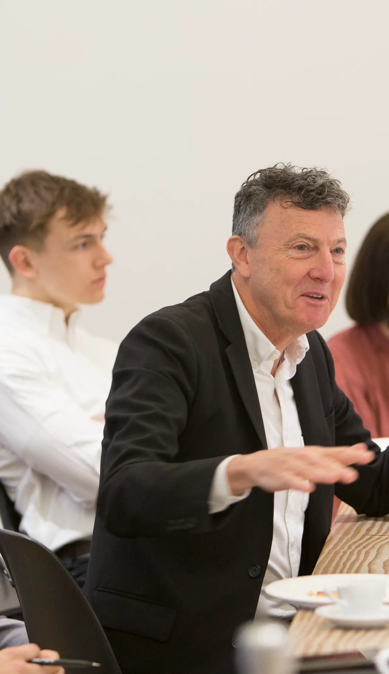 An image of Chris Williamson sitting at a table with team members expressing an idea.