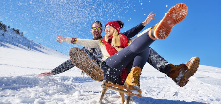 Happy couple sitting in their snow in their apres clothes and boots.