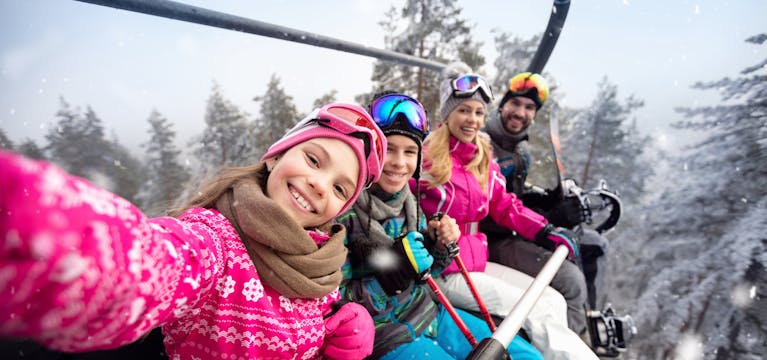 Family on a chairlift above a ski field.