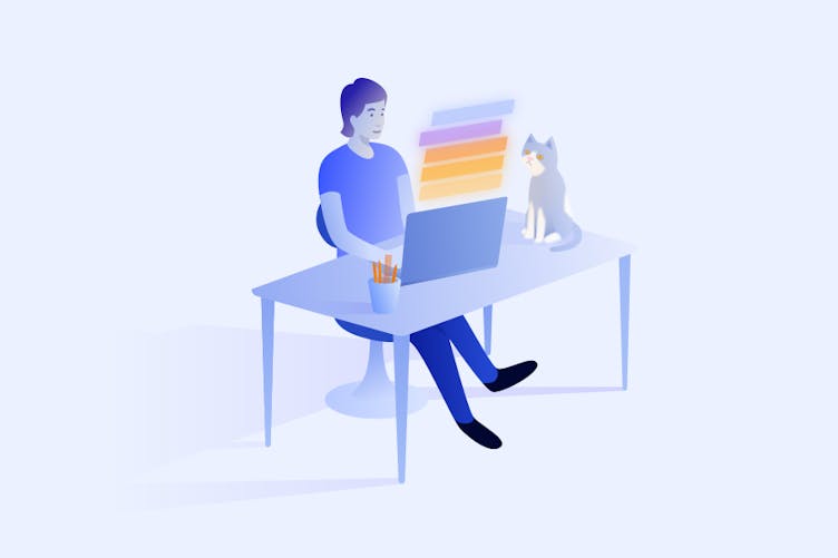 Man sitting at a desk looking on Jira on a laptop, accompanied by a sitting grey and white kitty.
