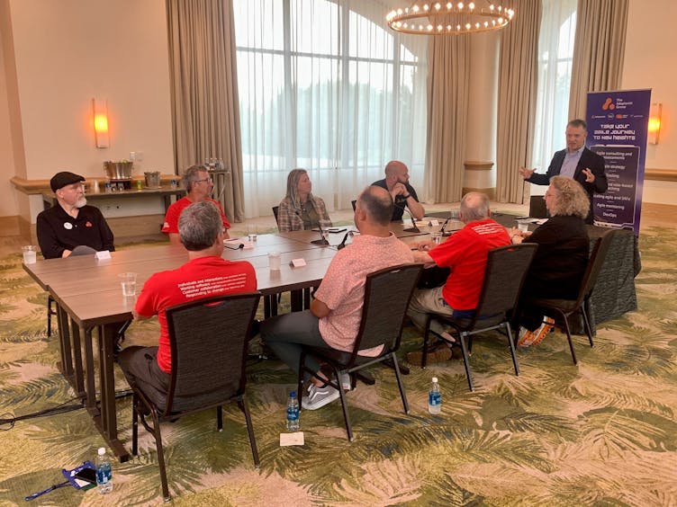 Agile experts around a table listening to one person speaking