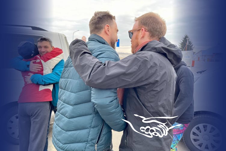 Neil patting Andriy on the back while Lou M embraced Maksym in a hug as they say goodbye at the Ukraine/Poland border.