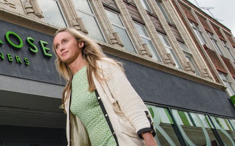 photograph of a person walking in front of a John Lewis Partnership shop